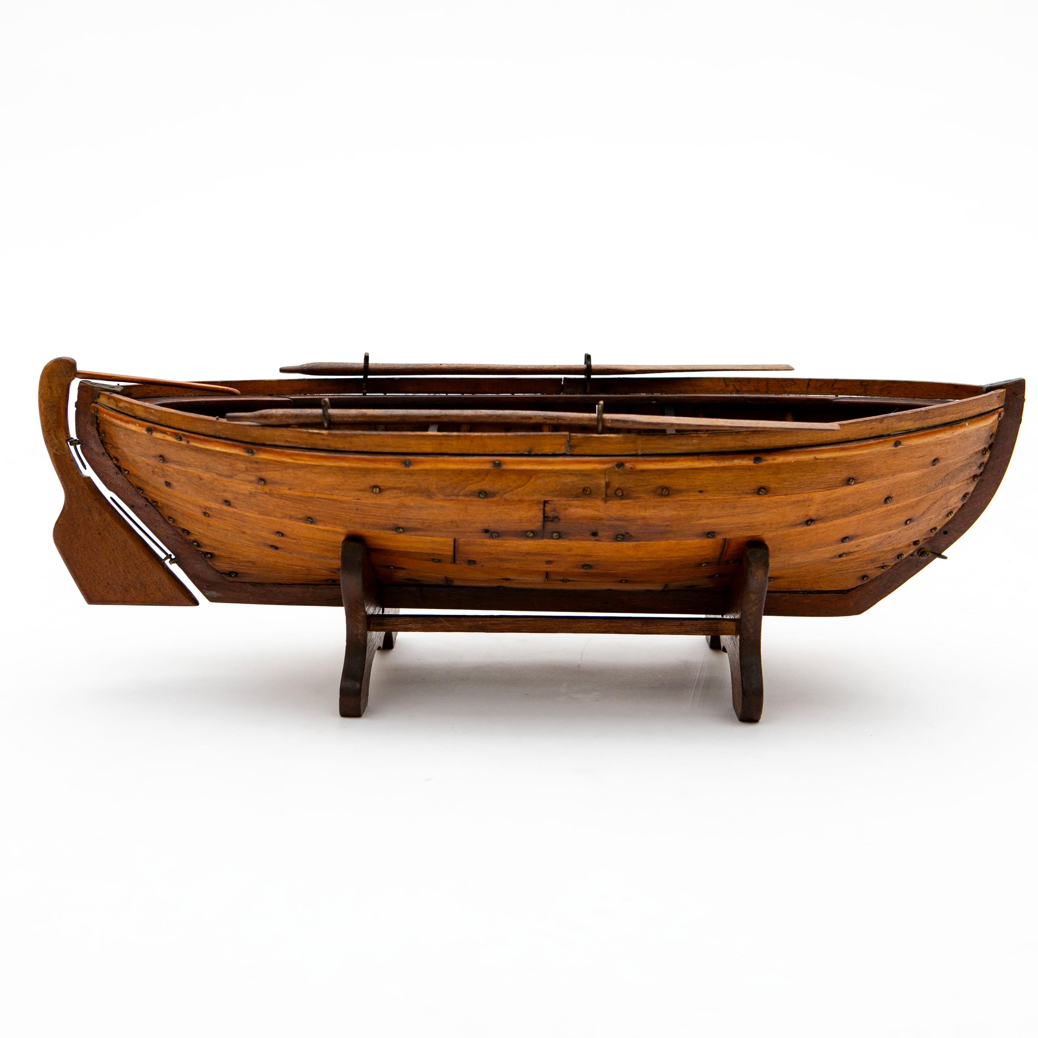 Un modèle de barque de haute qualité, d'excellente facture, réalisé en bois de tilleul et d'acajou avec des détails précis.
Les caractéristiques comprennent des fourches de pagaie en laiton et des vis le long de la coque, ce qui ajoute de