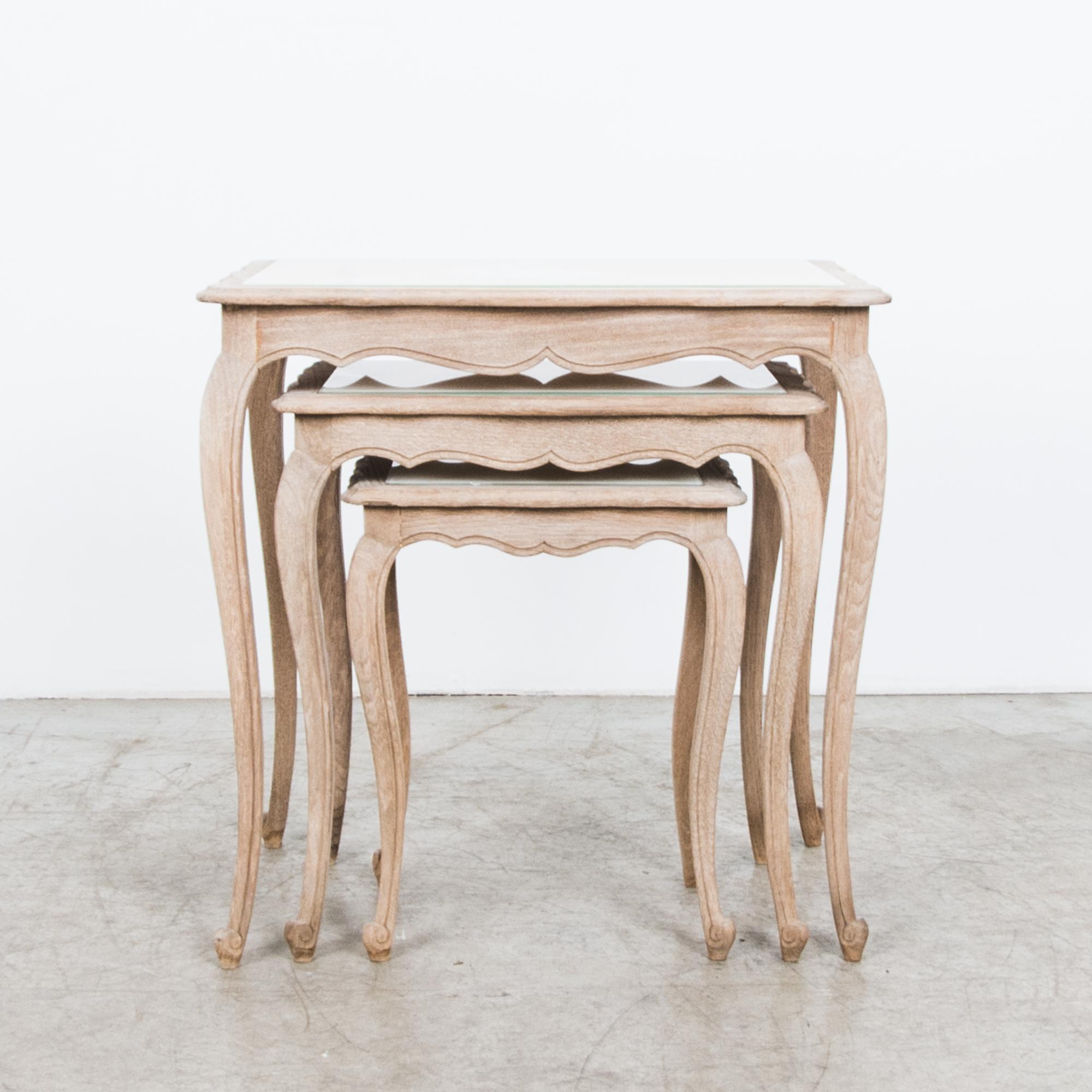 This set of three nesting tables from Belgium, circa 1950, combines oak with a white milk glass tabletop. Cabriole legs, a gently tapering tabletop profile and an elegant apron create a romantic silhouette, artfully updated by the light finish of