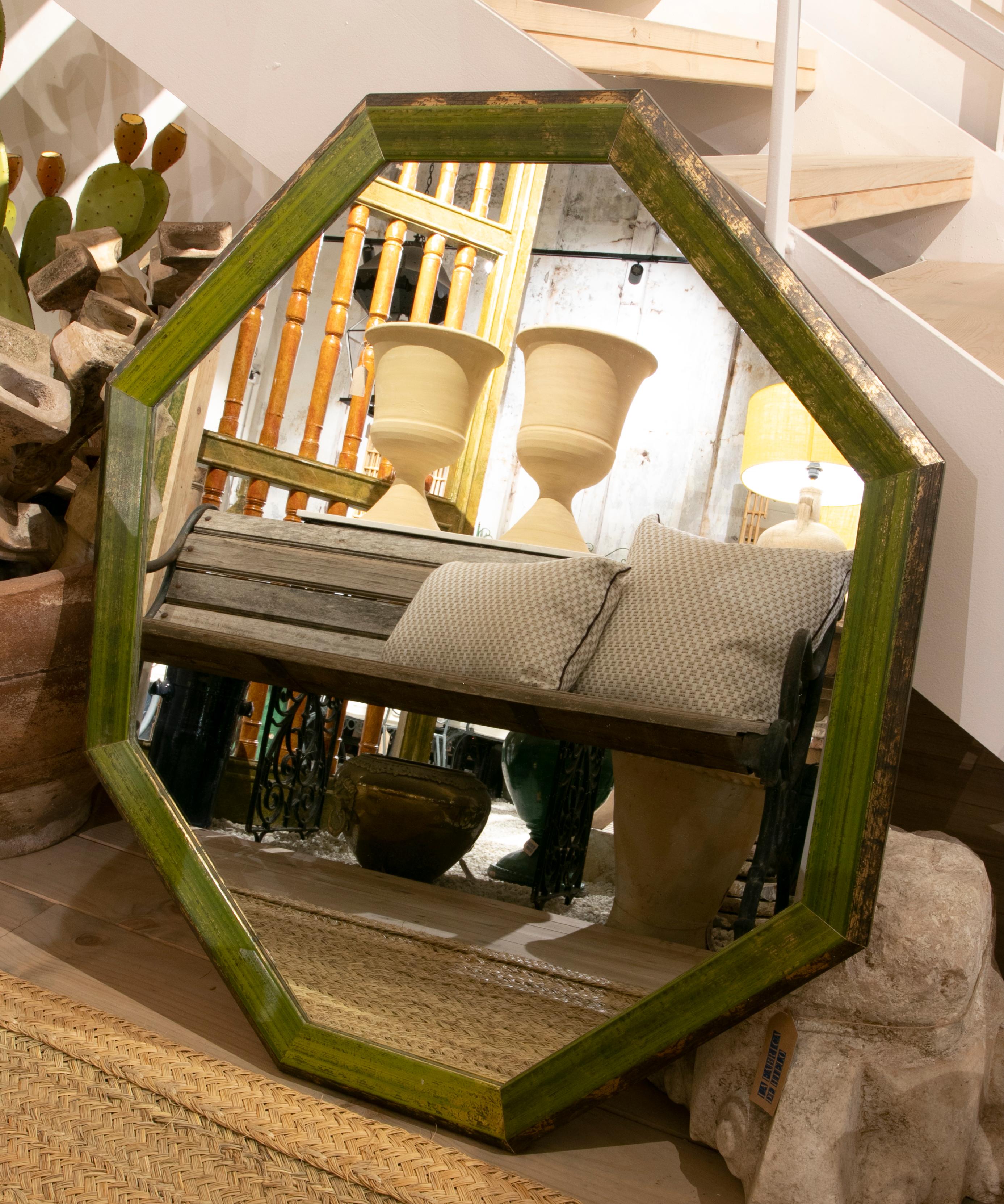 Wooden octagonal wall mirror painted in green.
 
