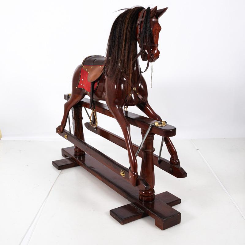 Polished modeled rocking horse in wood on stand with brass stirrups and horse hair mane. Please note of wear consistent with age.