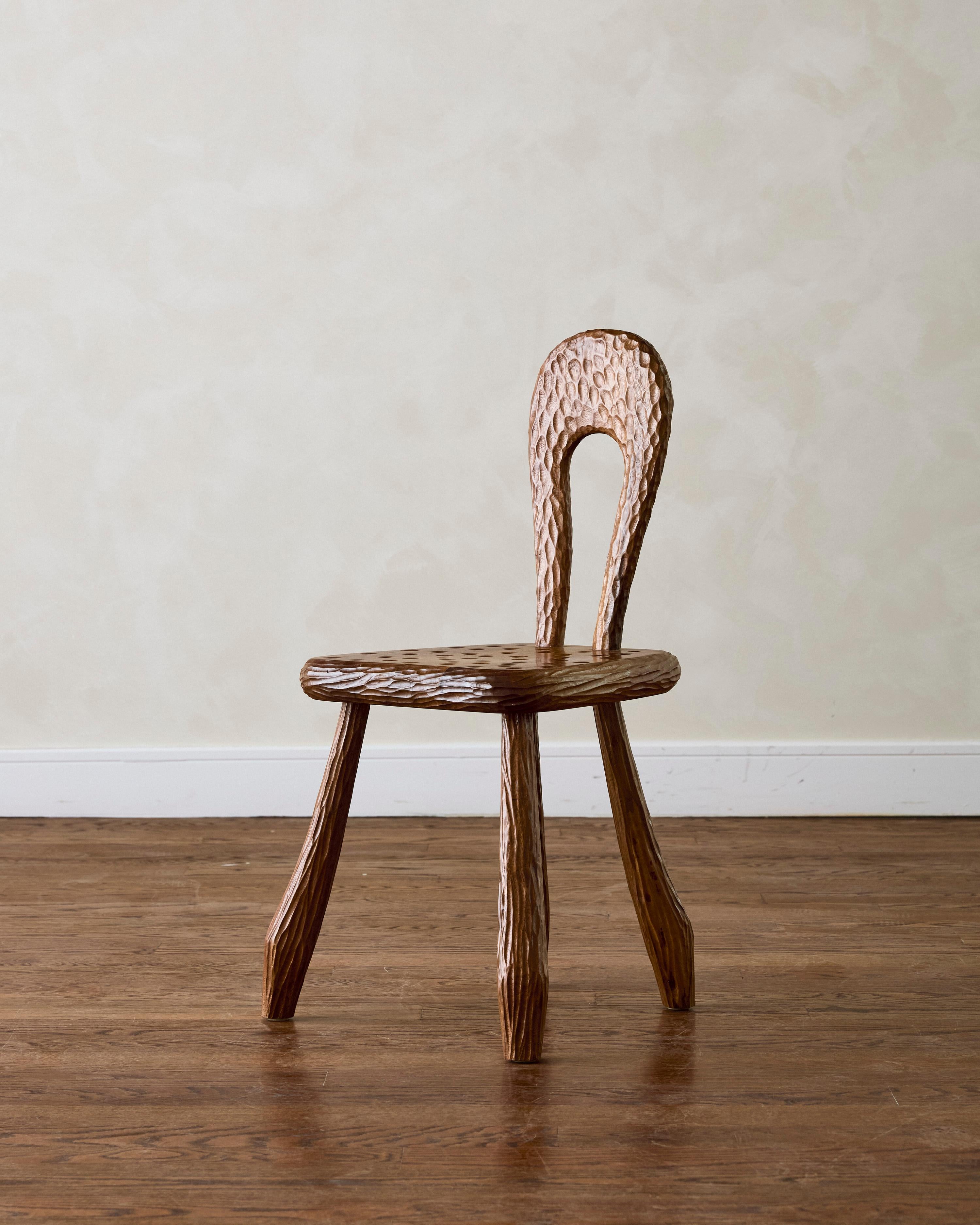 Wooden sculptural side chair featuring a keyhole backrest and carved indentations.
