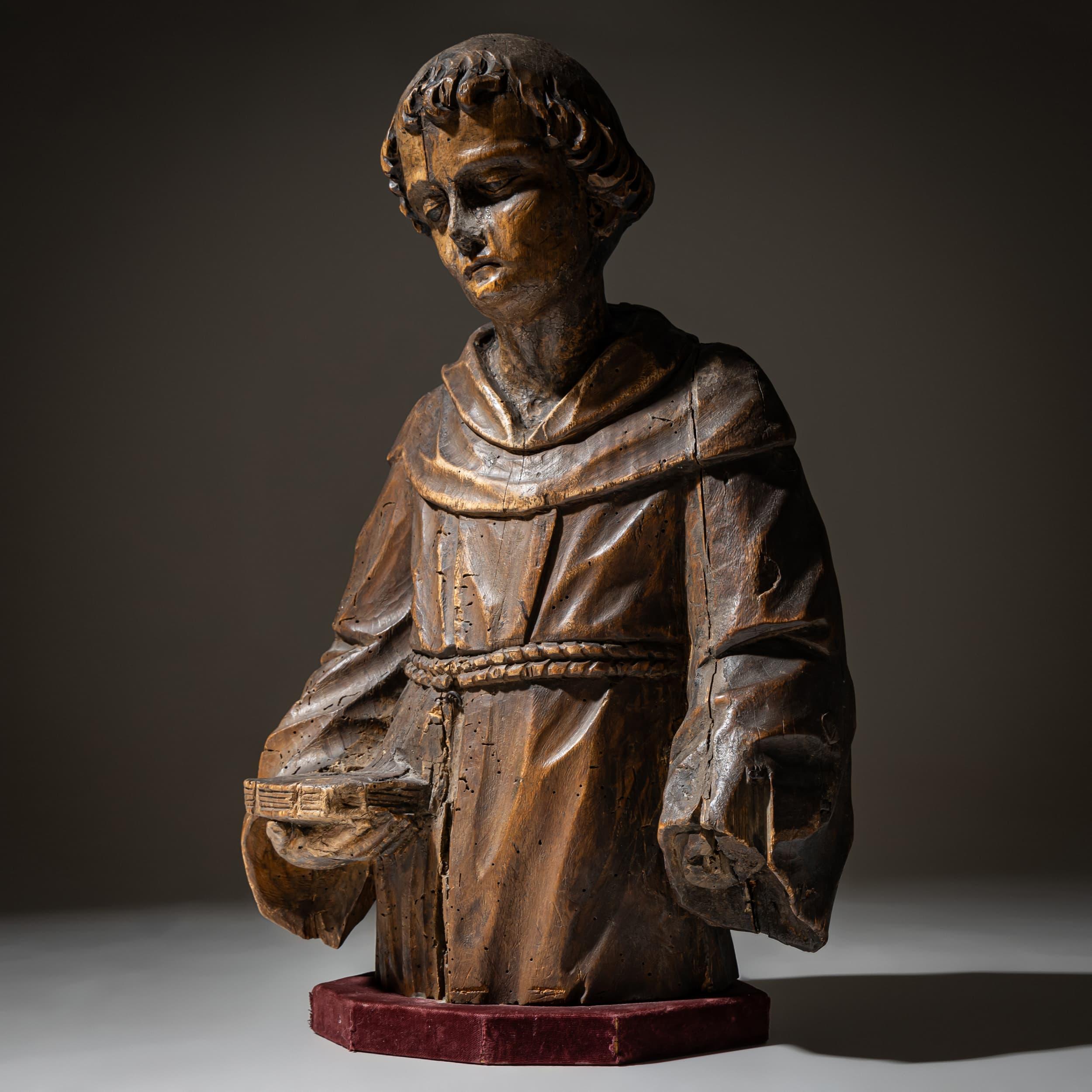 Espressiva scultura in legno di un frate francescano, probabilmente risalente al XIX secolo. La figura raffigura il monaco con lo sguardo abbassato, che indossa una tunica tradizionale con una cintura di corda. An He tiene un libro nella mano