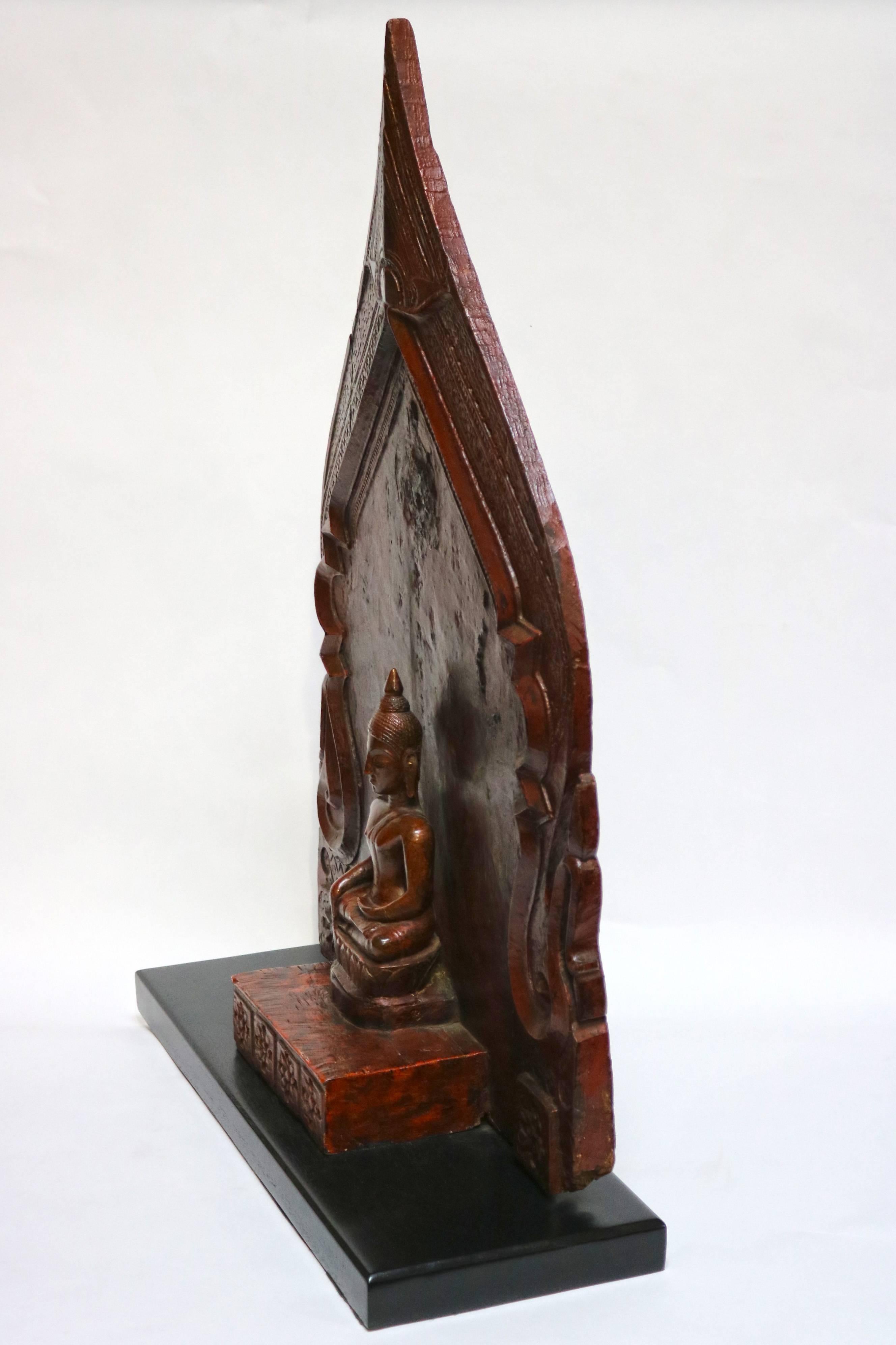 This wooden Buddha shrine was carved in 19th-century Thailand. Several layers of paint and lacquer cover the original wood, the most recent application being the red lacquer seen today. Traces of black and yellow provide evidence of the earlier