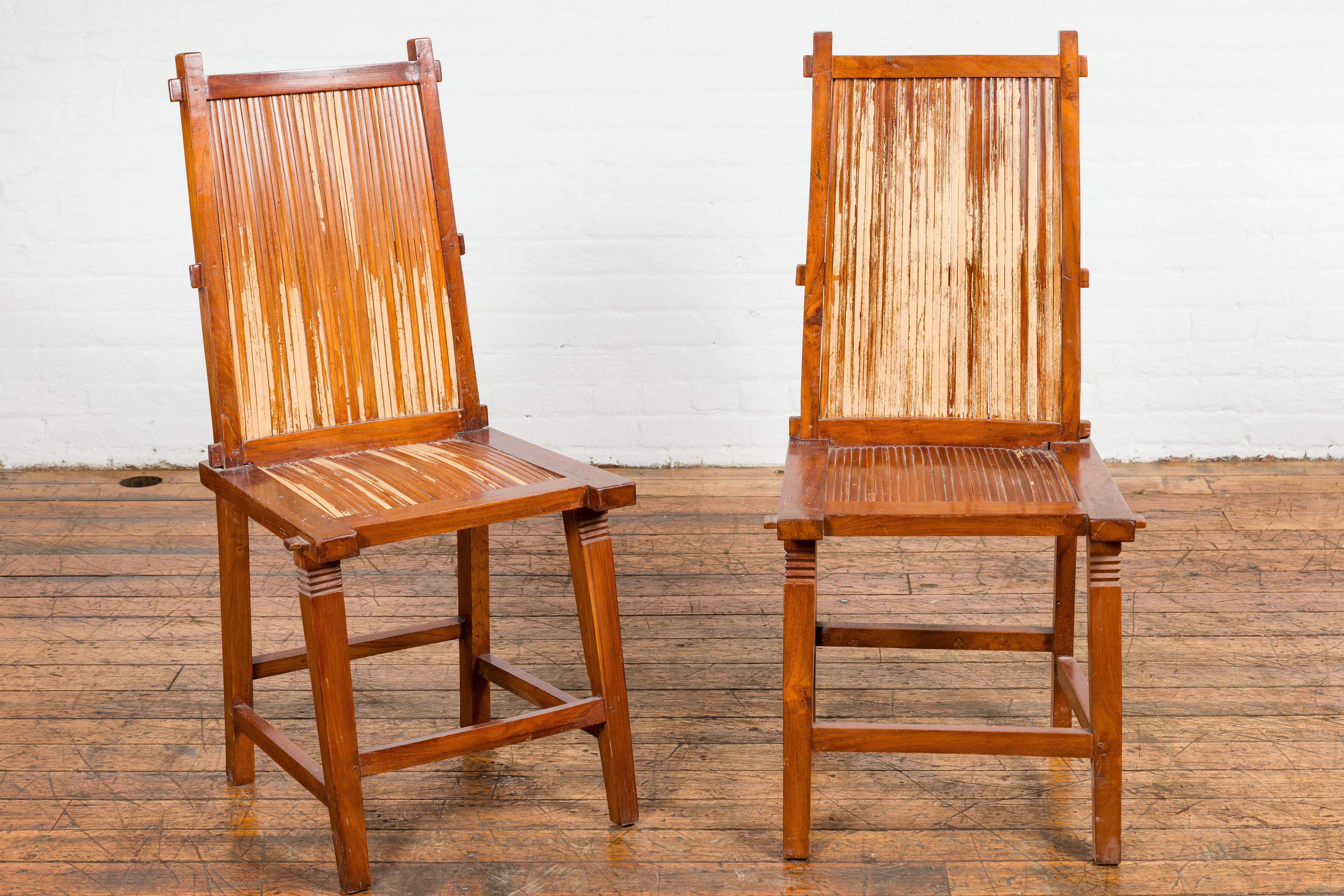 A pair of vintage side chairs from the mid 20th century with bamboo slats, tapered legs and distressed finish. This pair of vintage side chairs from the mid-20th century exudes rustic charm and timeless appeal. Crafted with a masterful blend of