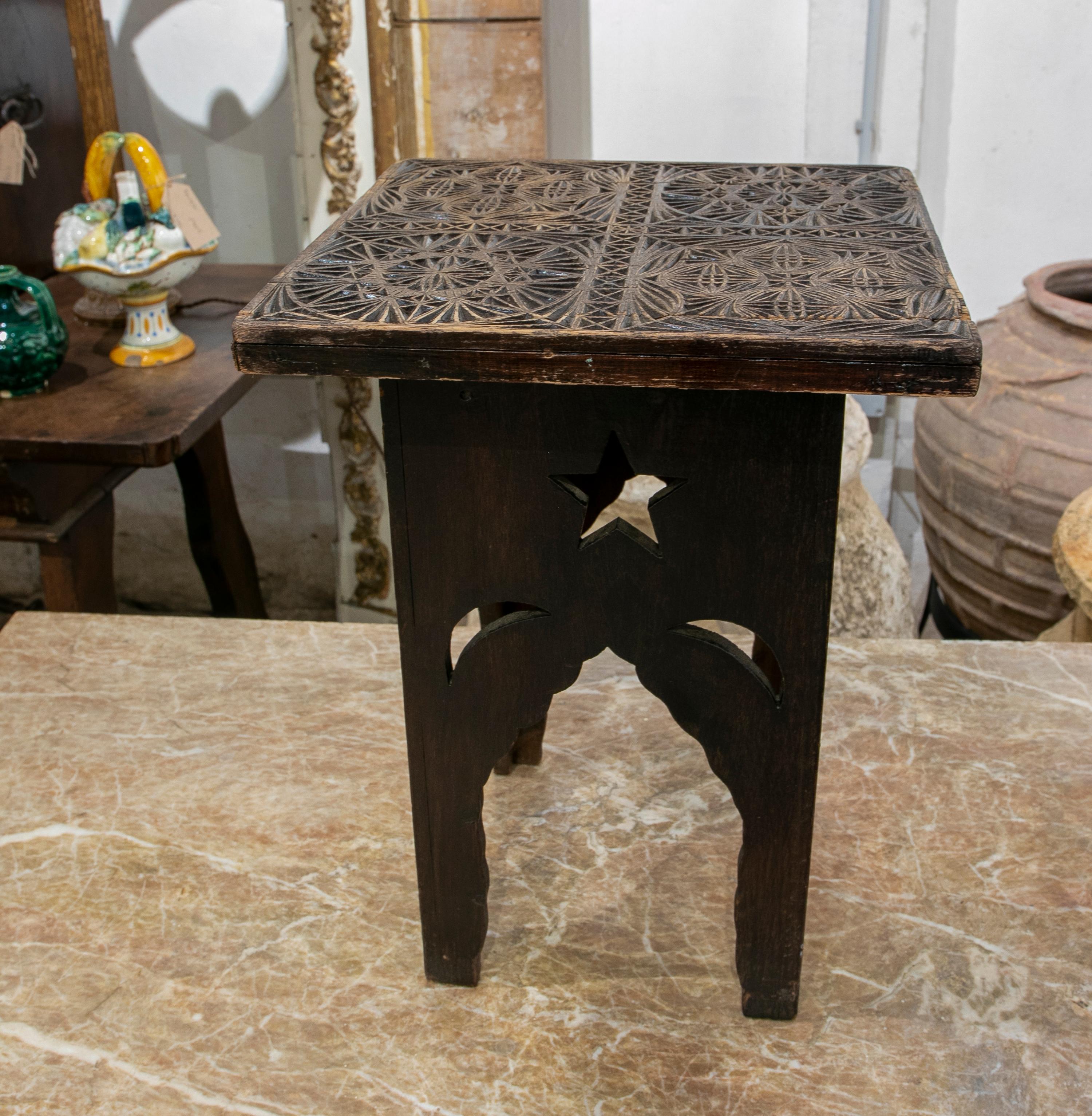 Wooden side table with hand-carved top with moulds for making fabrics.