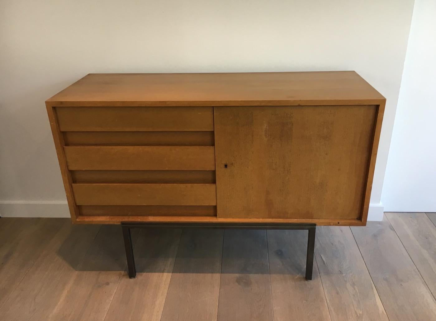 Wooden sideboard with one door and 3 drawers on a modernist steel base, circa 1950.