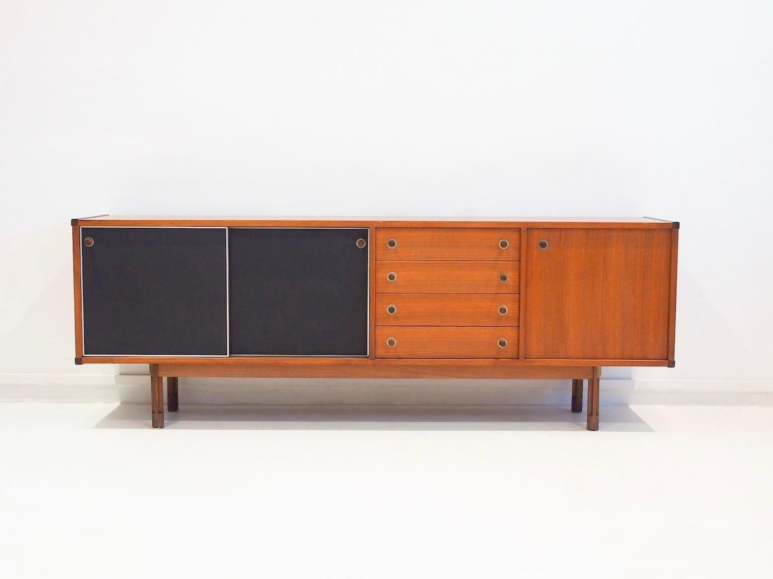 Teak sideboard from the '60s designed by George Coslin. Front with two black leatherette covered sliding doors, four drawers with felt interior and a smaller storage place with a shelf on the right. The doors and drawers are positioned slightly