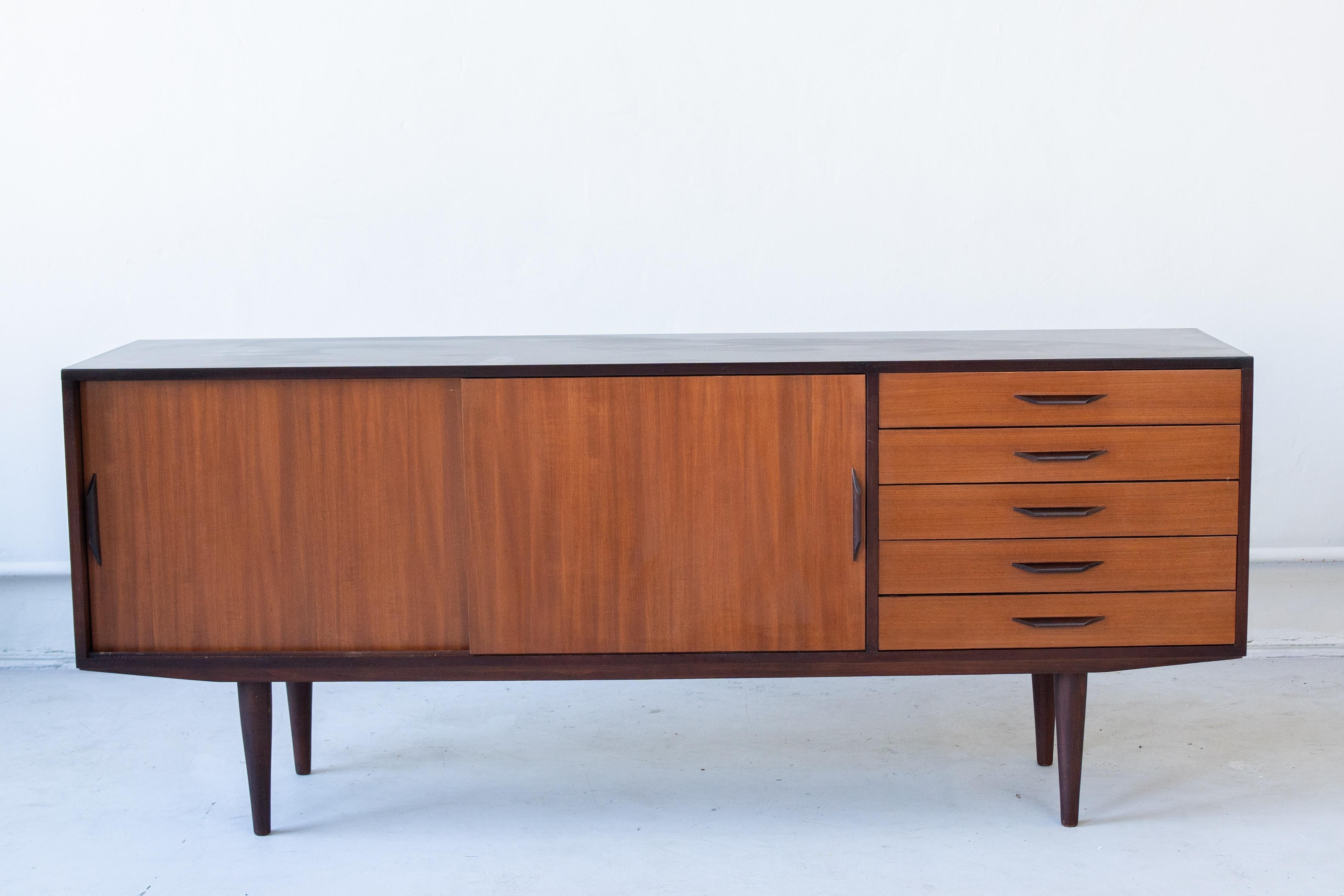 Mid-century, Danish stile wooden sideboard,
In the left hand side there are sliding doors, in the right hand side there are 5 draws. 
This piece is very elegant and functional.