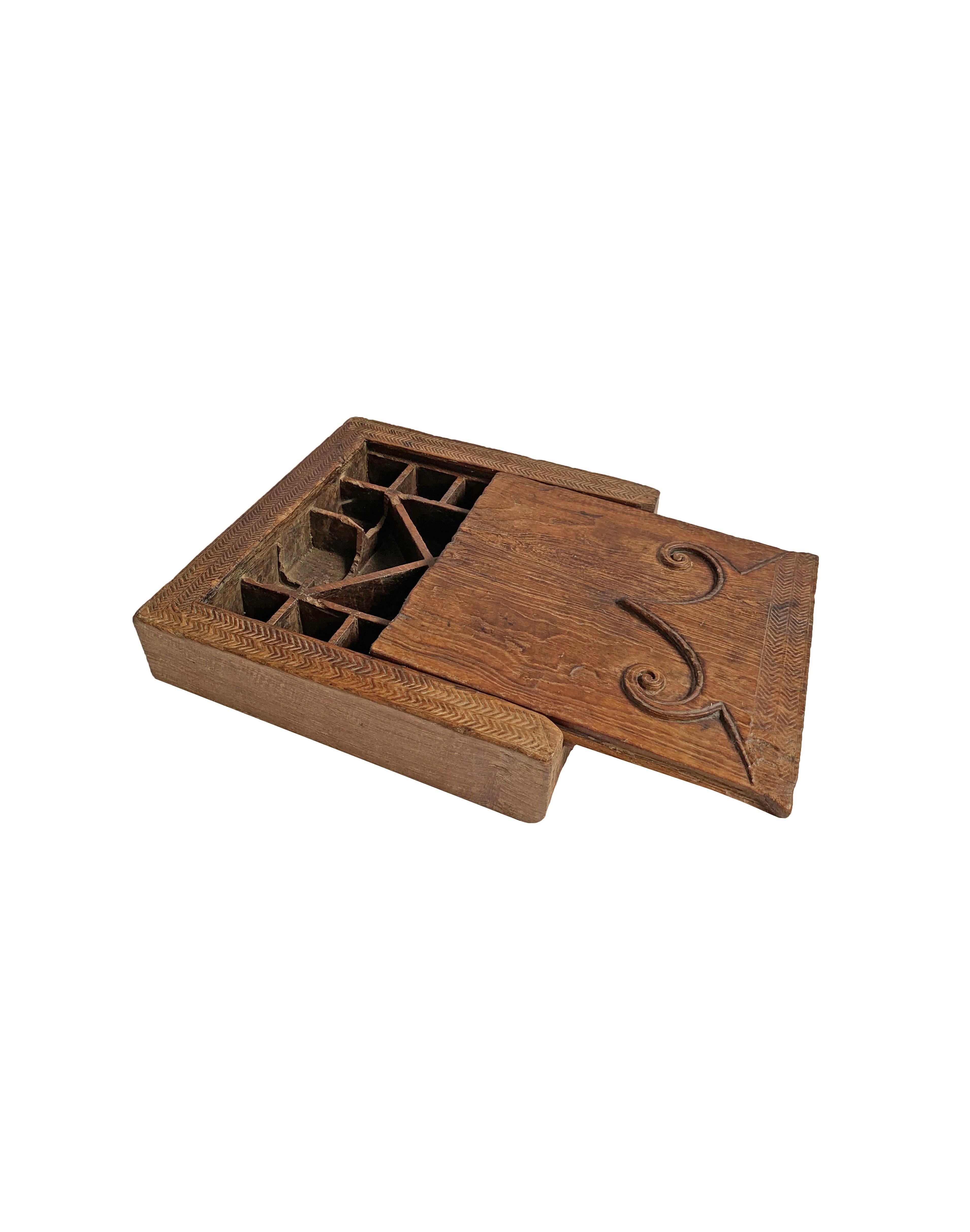 Cette boîte à épices provient de l'île de Nias, en Indonésie. Datant du début du XXe siècle, il a été fabriqué à partir d'un seul bloc de bois. Il est doté d'un couvercle coulissant, d'une élégante texture de bois et d'étonnantes gravures tribales