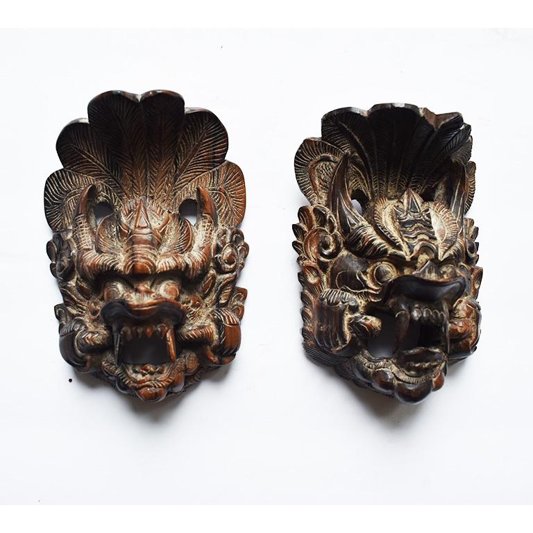 A pair of hand carved dark stained wood decorative wall hangings from Thailand. Miniature in size, this set would make a great conversation piece either hung on a wall or lying creatively on a table. 

One piece has a small chip in the wood at the
