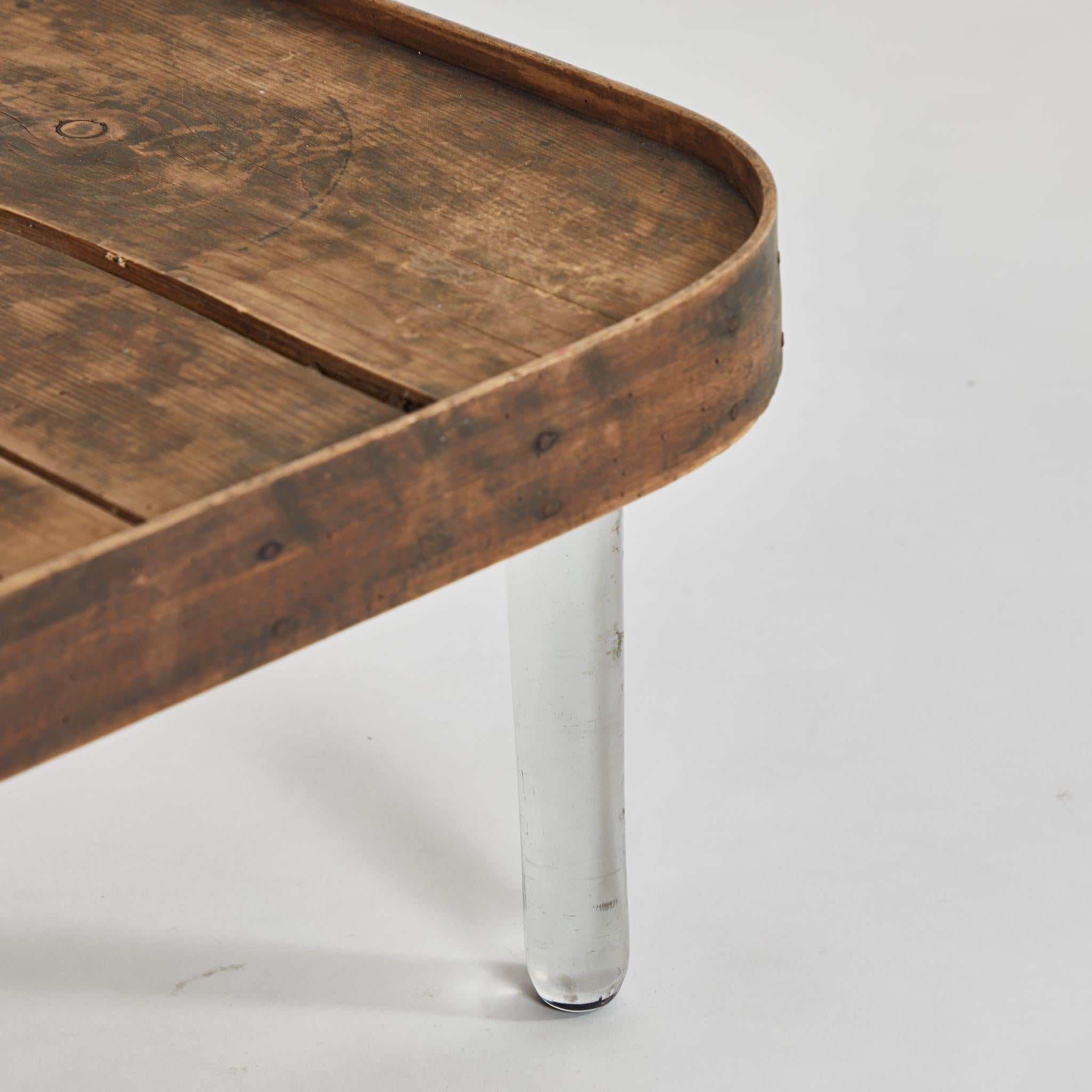 Late 19th-century French wooden tray-top table with clear glass legs. Chic and modern, the delicate appearance of the legs makes a wonderful contrast with the earthy, industrial-feeling top; it almost appears to be floating in space. 

France, circa