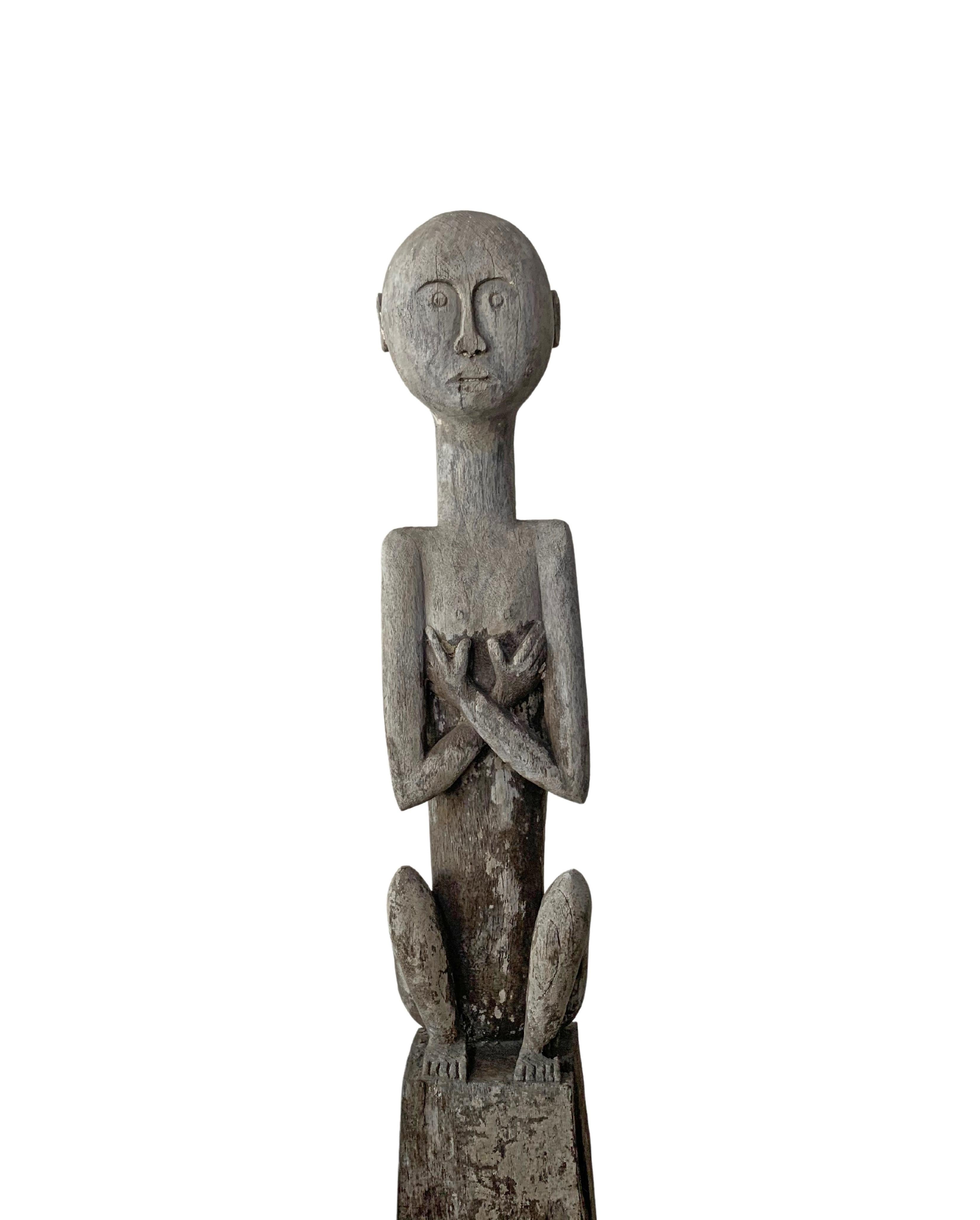 This wooden sculpture of an ancestral figure originates from the Island of Sumba in Indonesia. It features a wonderful age-related patina and wood texture. Carved from a single block of wood the sculpture is mounted on a black iron Stand. The