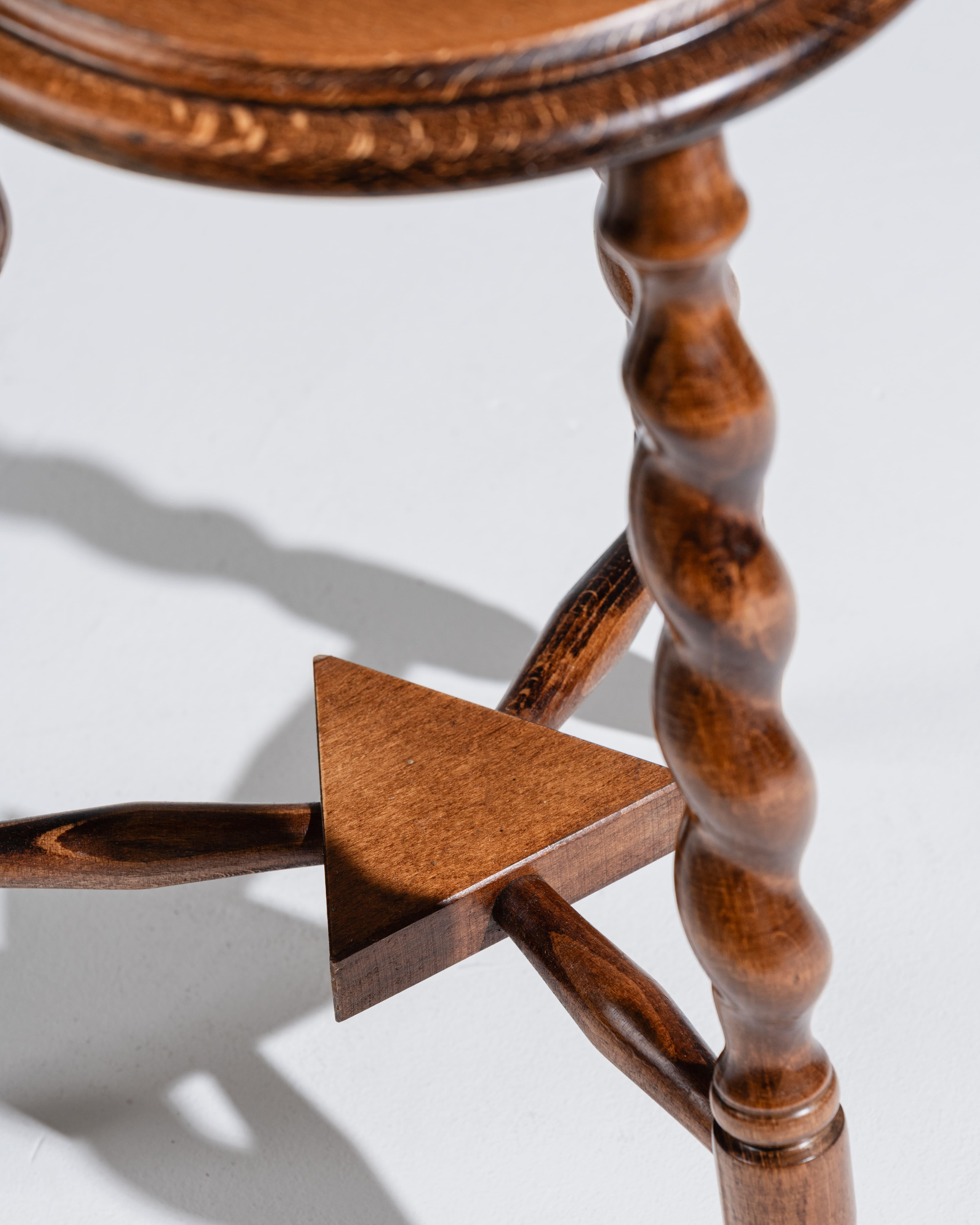 Dreibeiniger Hocker aus gedrechseltem Holz, der auf drei verdrehten Beinen steht, die durch eine zentrale Querstange verbunden sind. Französische Handwerkskunst aus den 1950er Jahren. In gutem Zustand, mit einer schönen Holzpatina.