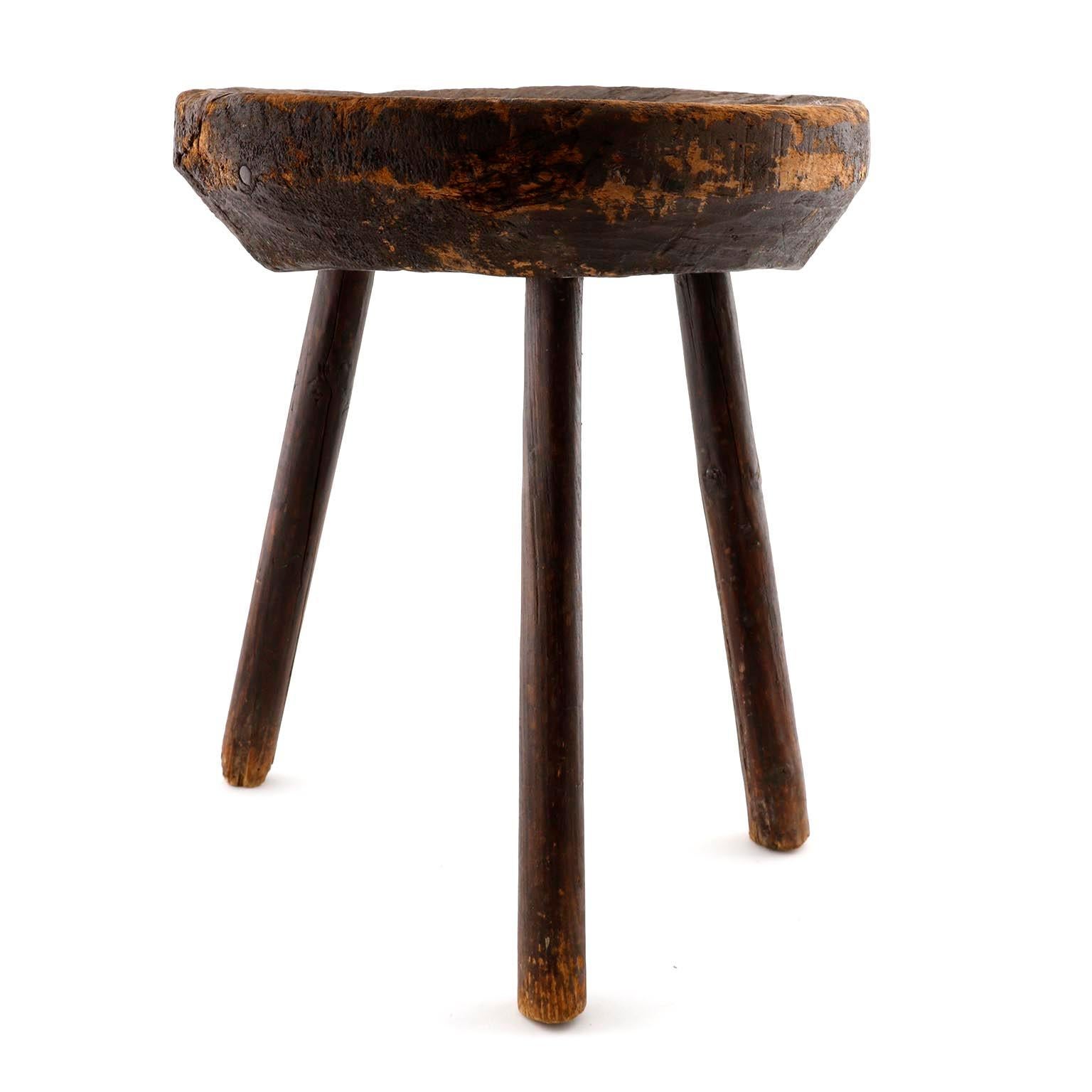 A vintage solid dark wood stool with great patina and three splayed legs.
On one side there is a carving which is probably a grip.
This stool is very likely an early European milking stool to milk cows.