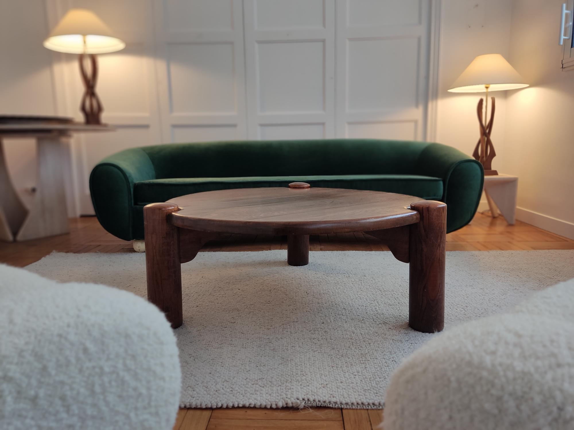 Dreibeiniger und runder Couchtisch aus Eiche aus den 1960er Jahren.
Die zylindrischen Beine passen sich von außen an die runde Form des Tisches an. Diese Koketterie sowie die schönen Proportionen verleihen diesem Edelholztisch viel Stil.

