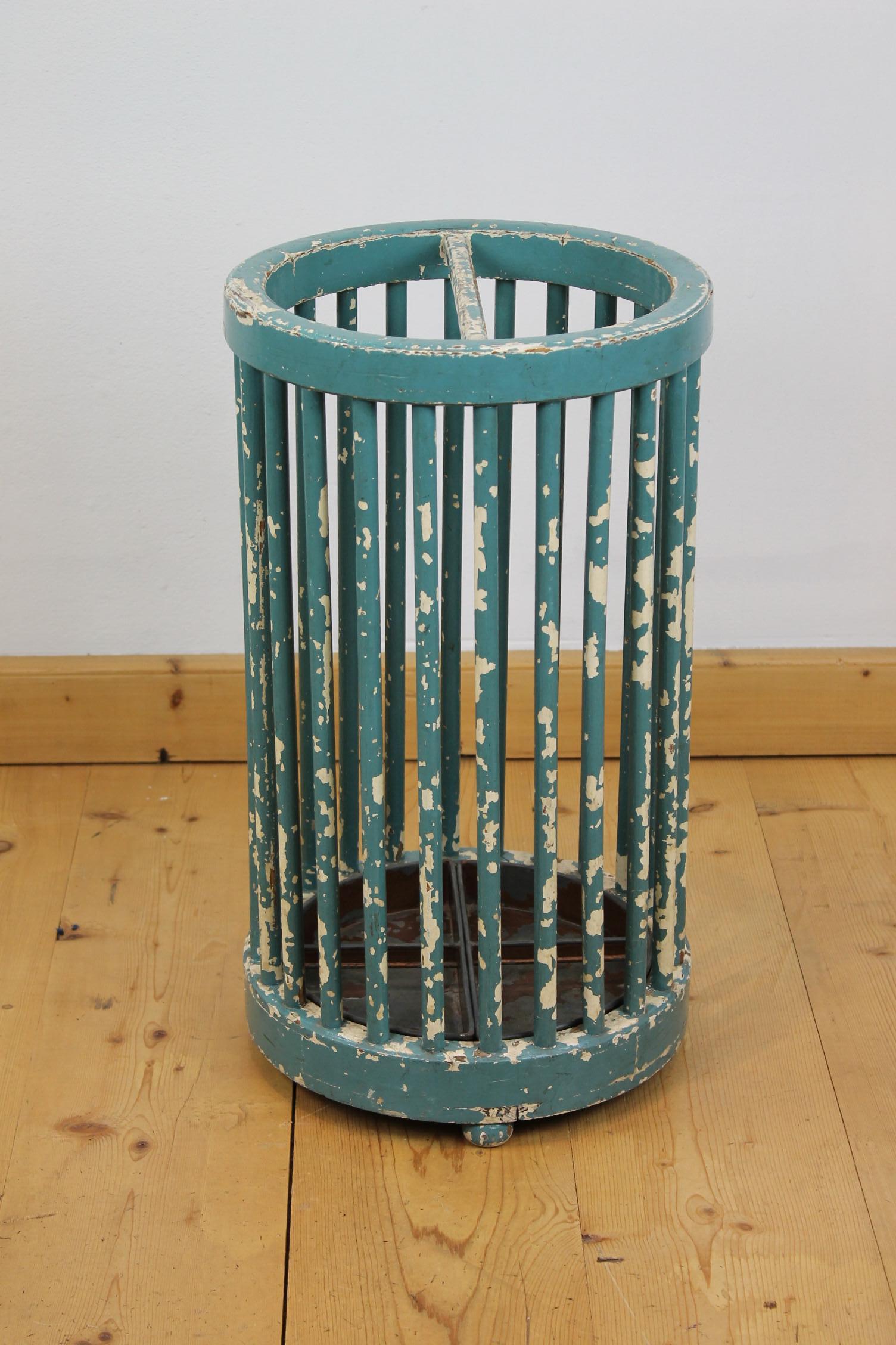Wooden umbrella stand with a great worn patina. 
This large round umbrella stand has the color turquoise green and could also be used to storage roll-up charts or maps. 
It it made of painted wood with bars all around and 2 zinc plates under for
