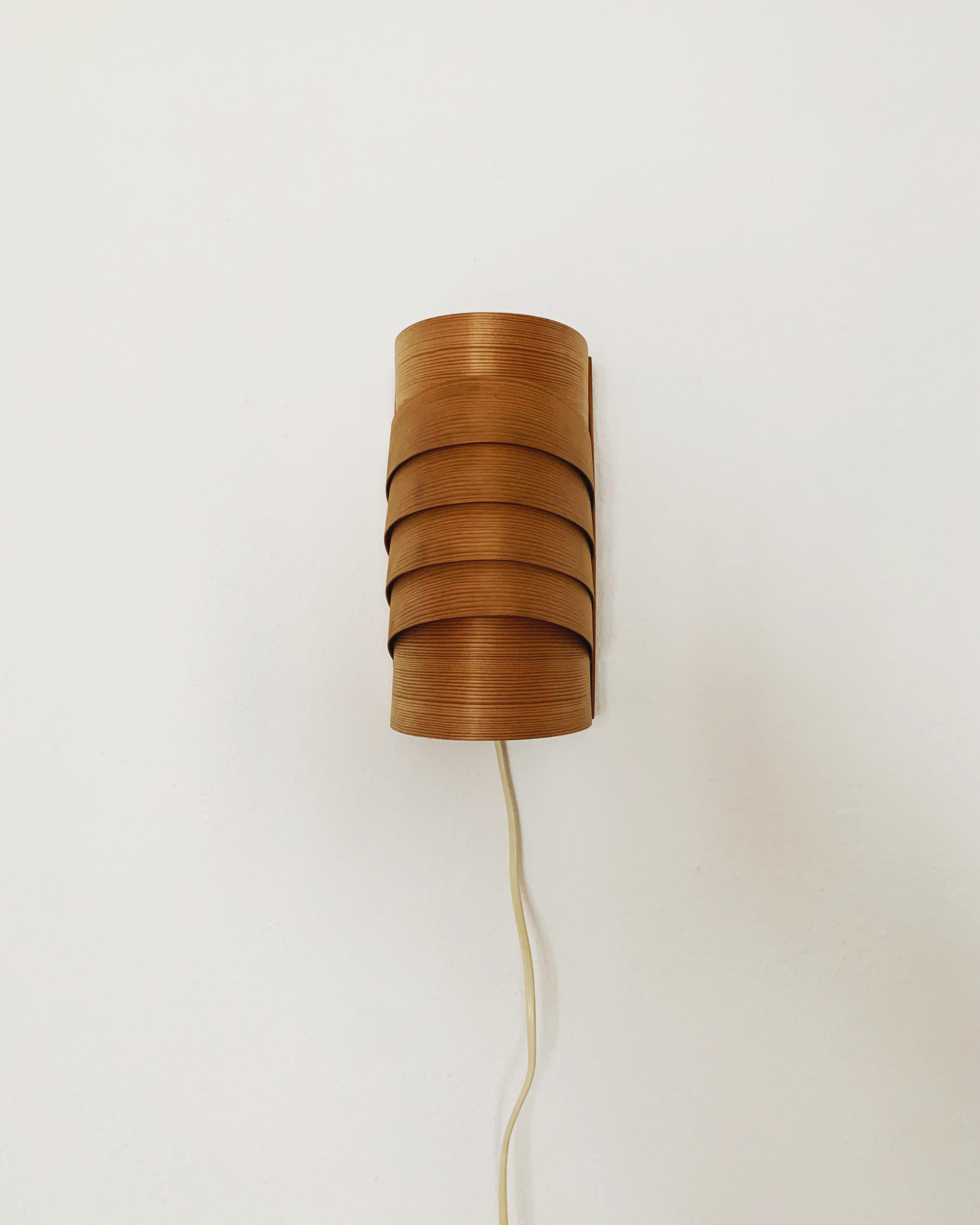 Extraordinarily beautiful wooden wall lamp from the 1960s.
Loving and high-quality processing.
The design and the material create a very warm and pleasant light.
The play of light created by the slats makes the lamp even more