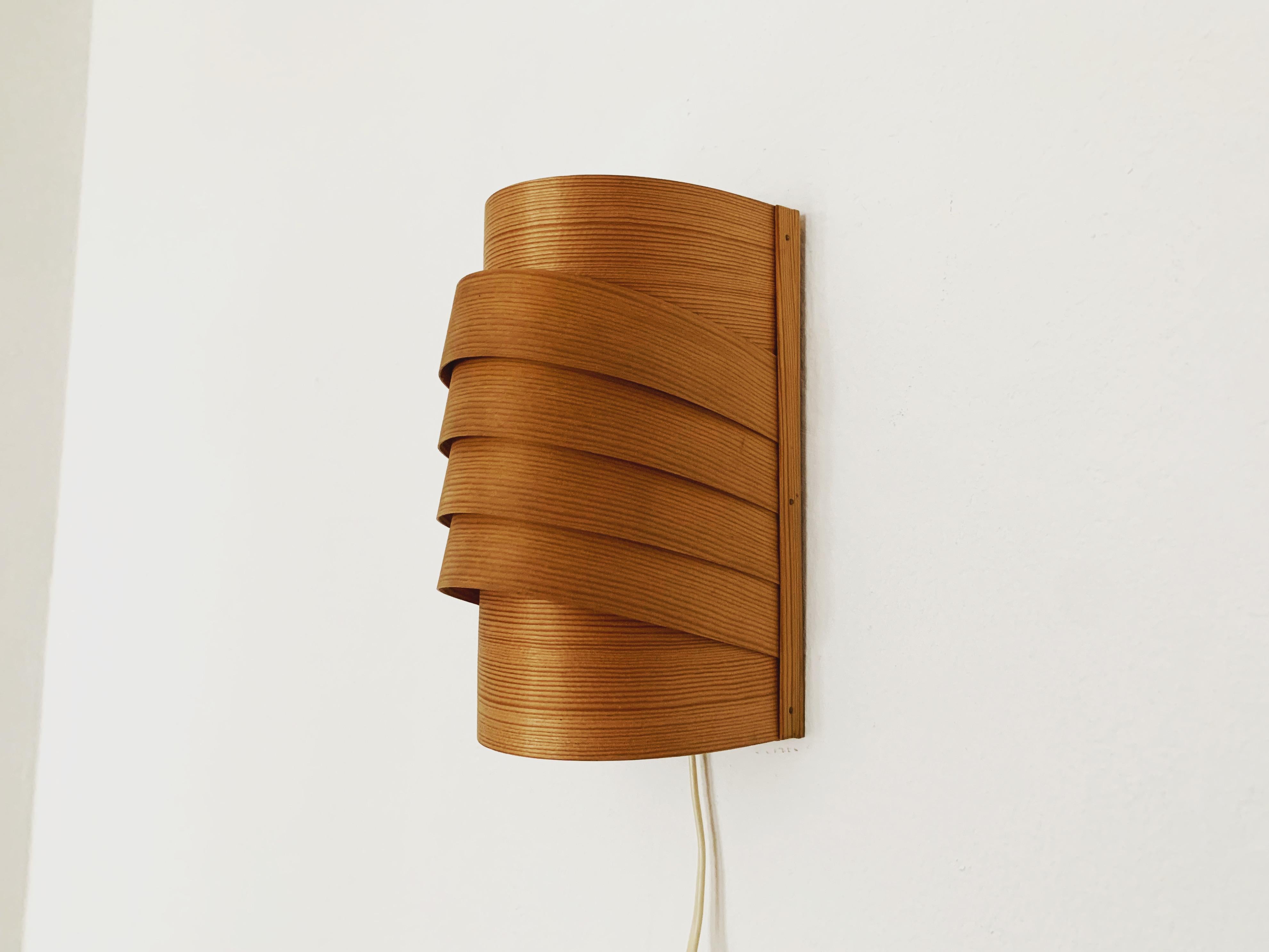 Extraordinarily beautiful wooden wall lamp from the 1960s.
Loving and high-quality processing.
The design and the material create a very warm and pleasant light.
The play of light created by the slats makes the lamp even more