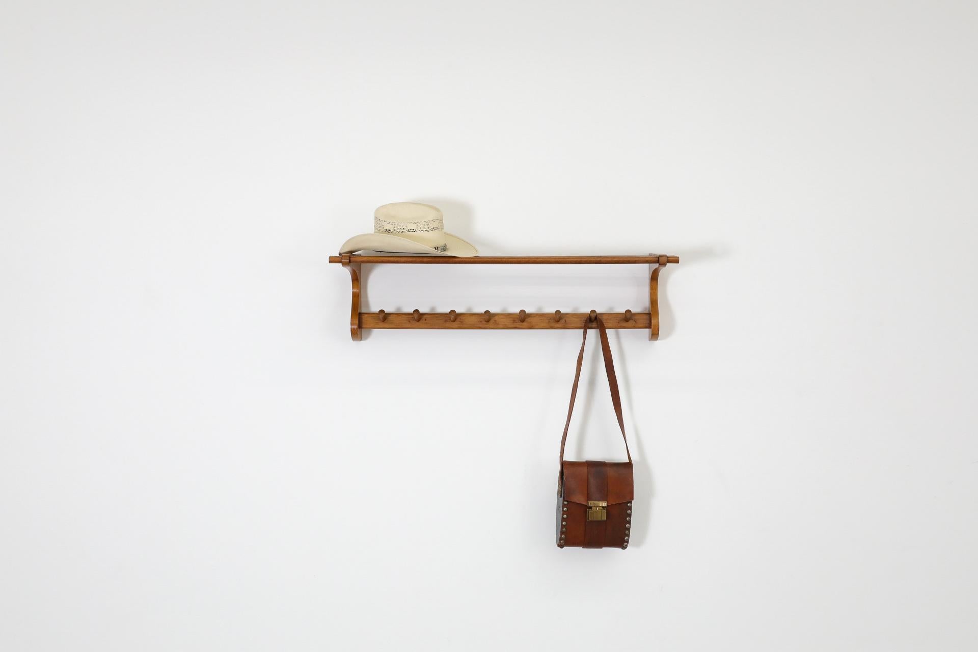 Wall mount coat rack by 't Spectrum, 1950s. This coat rack has 8 hooks on lower bar and a doweled shelf on top for hats or storage. In original condition with visible wear consistent with its age and use.
