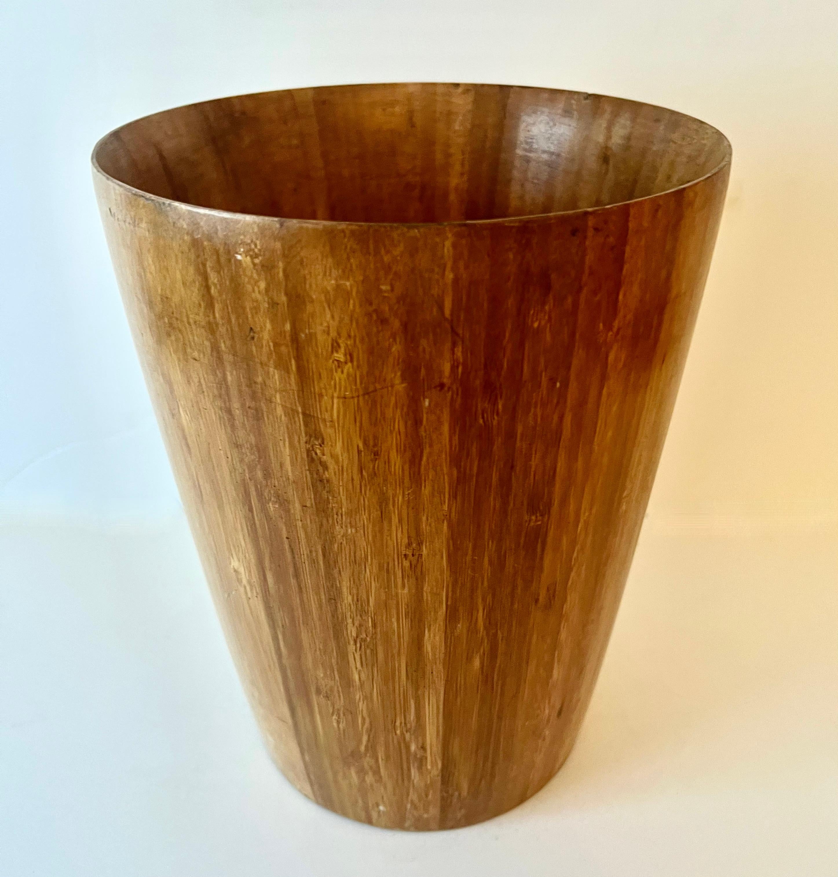 A wooden waste can or waste bin.  A compliment to many space and especially next to a desk or work station.  A very neutral and simple design - the wood is striated and beautifully put together.  

A wonderfully simplistic piece for any room.  The