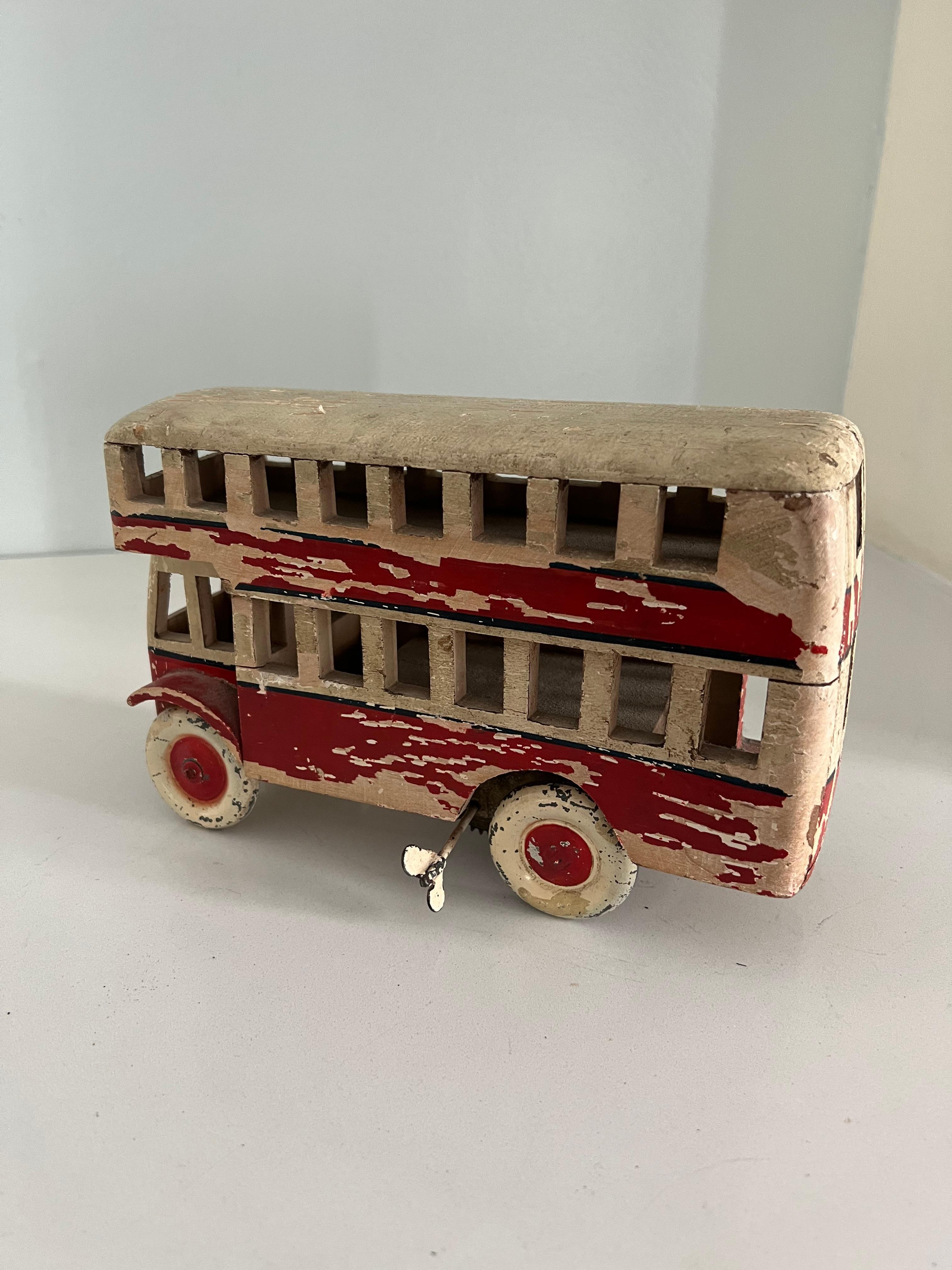 Charming painted wooden wind-up patinated white / red double-decker bus. Raw wood peeks through the original paint to make for a pleasing texture and patina. A compliment to bookshelves and baby rooms. A fun and captivating display piece. While it