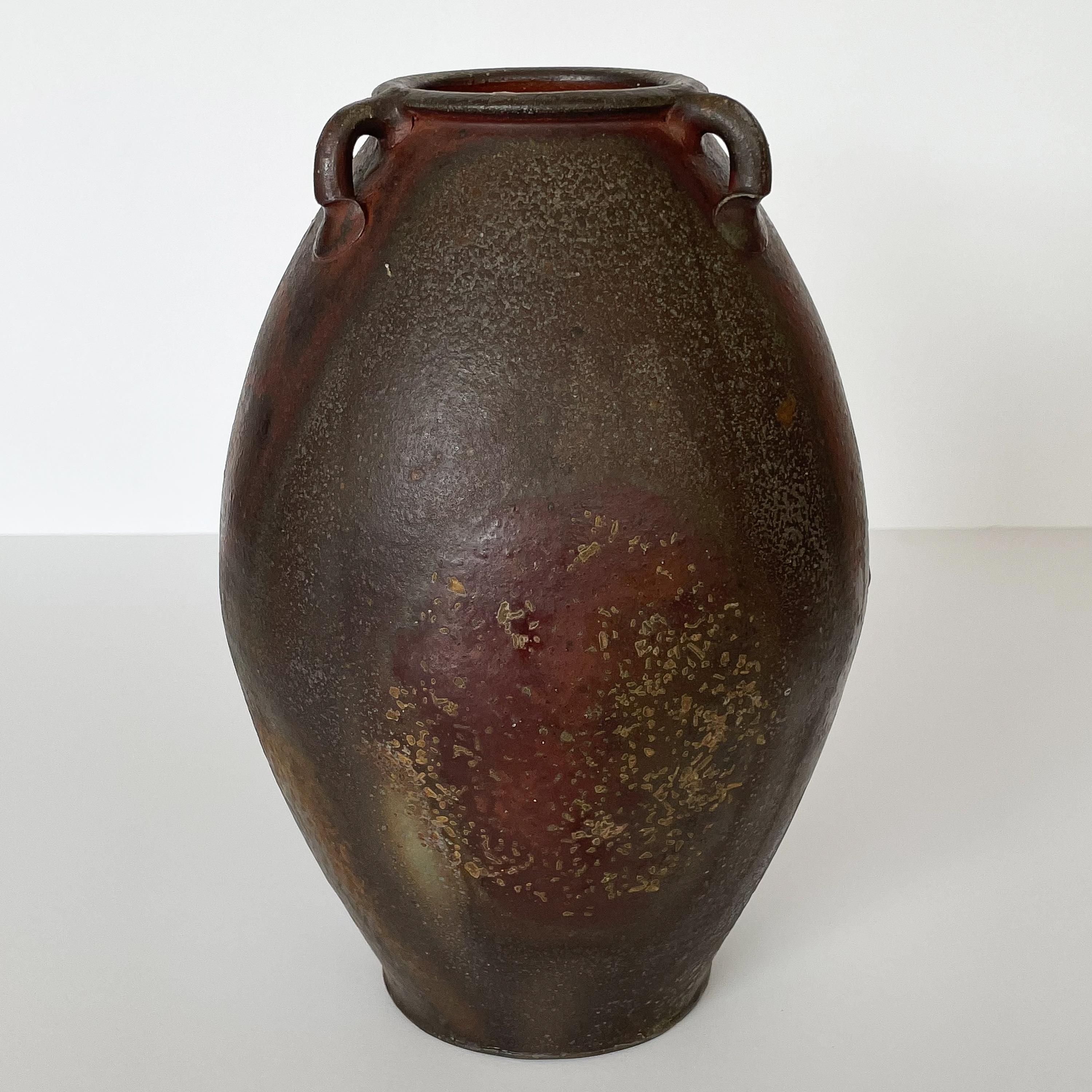 A beautiful woodfired studio pottery vase by a North Carolina artisan, circa 2020. Hand thrown stoneware vessel / amphora with three handles. Woodfired for three days with oyster shells to create a natural dramatic glaze in earth tones and rust red.