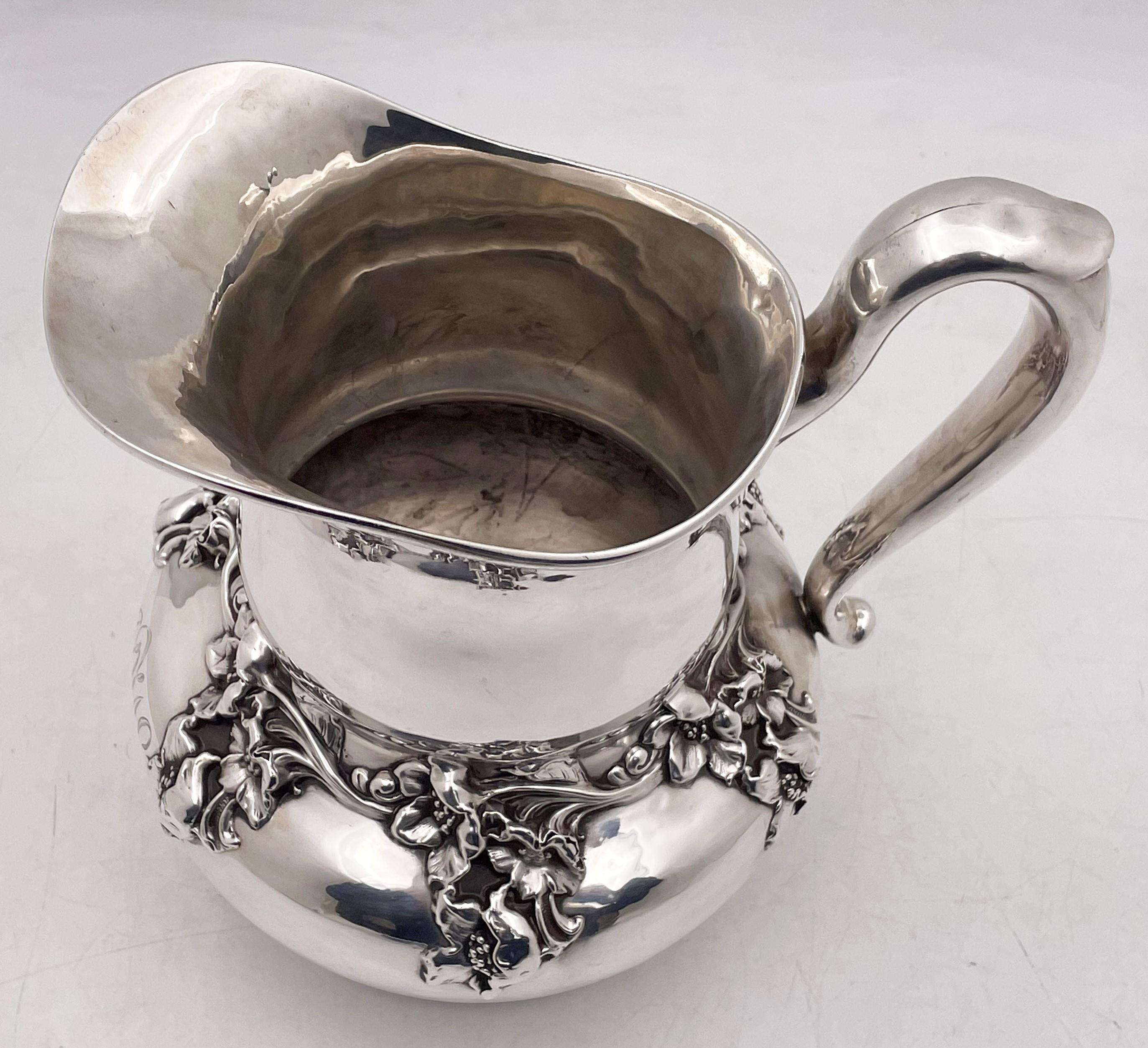 Woodside, sterling silver water pitcher, from the early 20th century, in Art Nouveau style, showcasing beautifully rendered dimensional flowers and leaves. It measures 8 1/3'' in height by 8 1/3'' from handle to spout by 6 3/4'' in depth, weighs