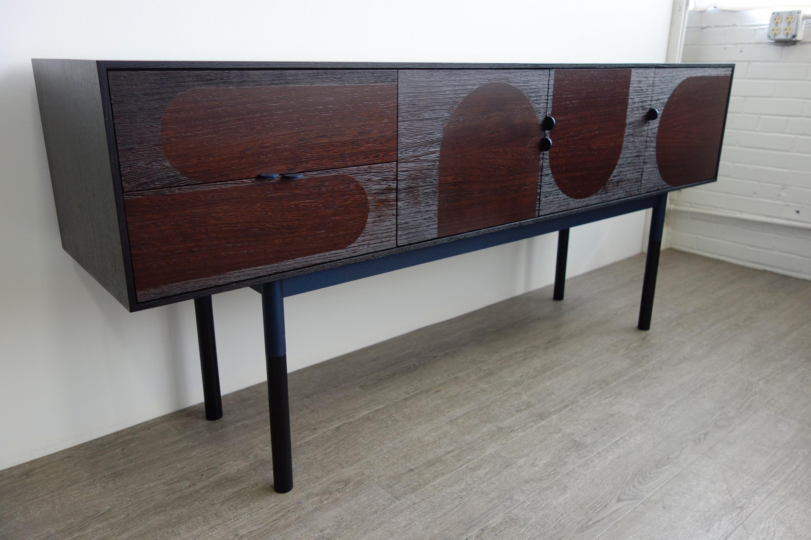 Sleek sideboard made of wengé, ebonized rift-sawn oak and steel. The doors are constructed of hand-sliced African wengé veneer and then media blasted to expose graphic arch patterns. The effect is stunning but subtle as the coarse texture reflects