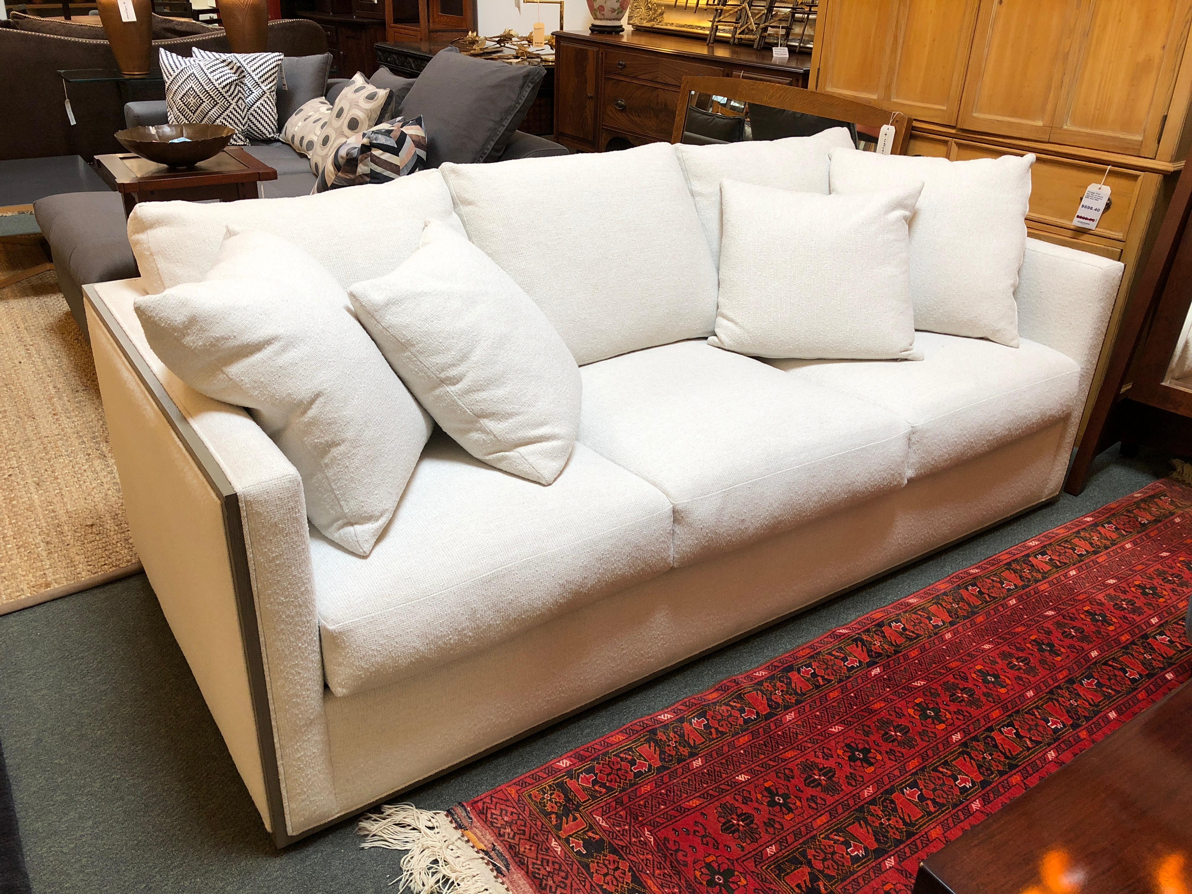 A New Woody sofa, by Rene Cazares furniture. Fluffy down and feather wrapped foam cushions rest on a kiln-dried hardwood frame and sinuous springs. The tailored upholstery is a nubby woven fabric. The silhouette is outlined in cerused grey wood. Two