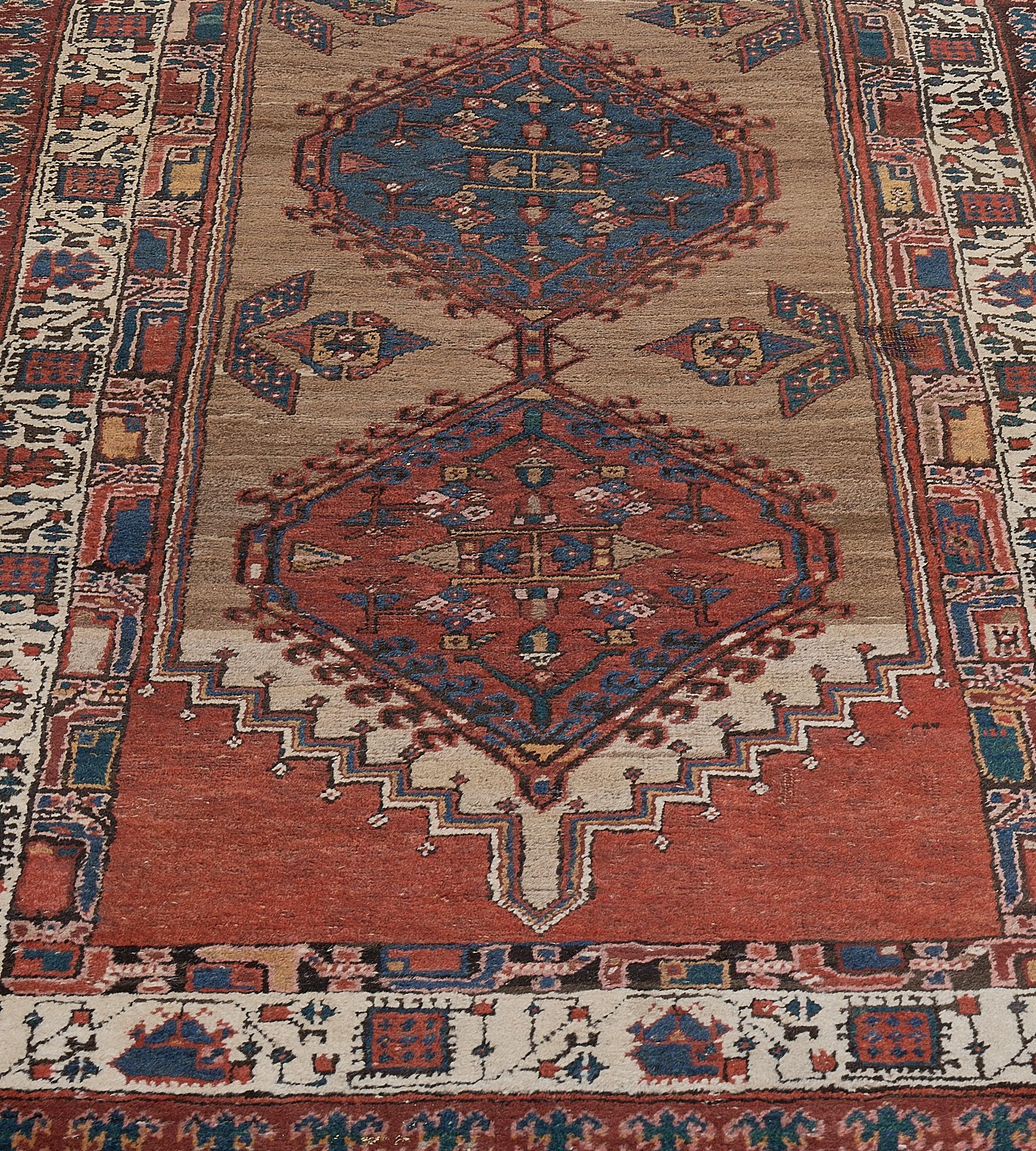 This antique Serab runner has a camel-brown field with a two pair of stylized leaves issuing flowerheads around a central column of three terracotta-red and blue hooked linked lozenges each containing a central open panel surrounded by a delicate