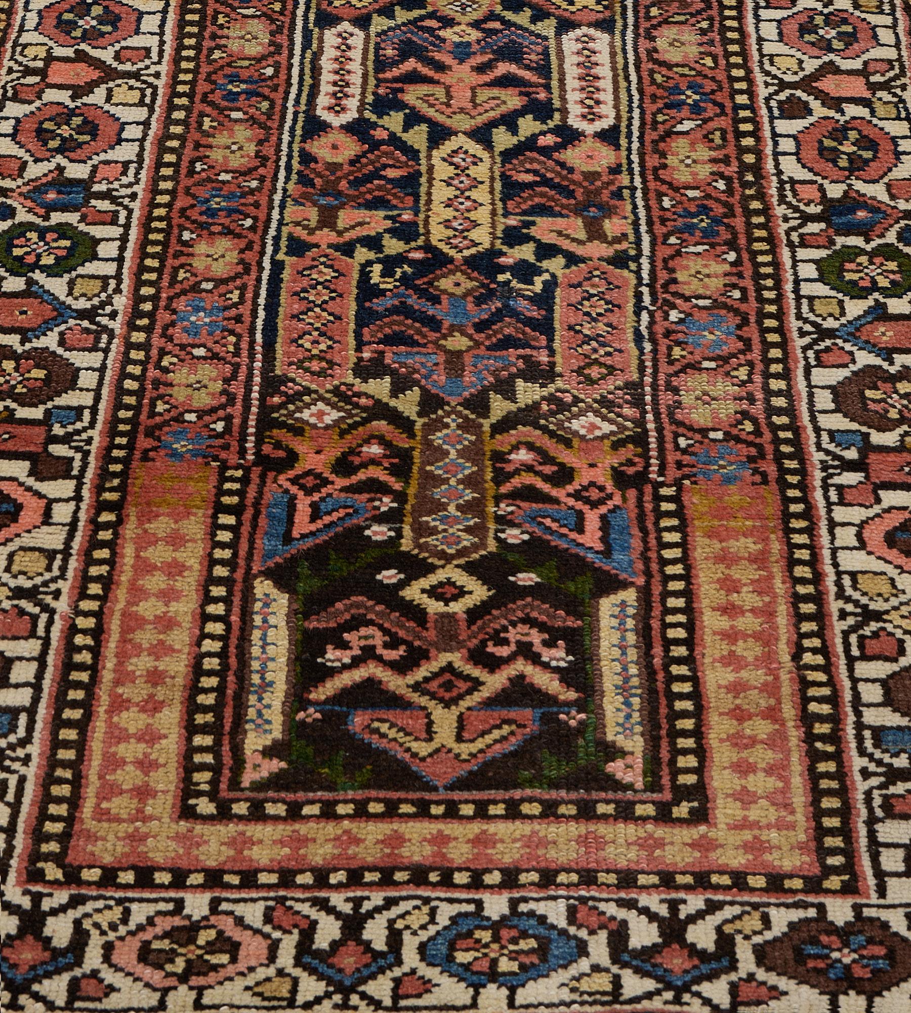 This antique, circa 1900, Persian Kurdish runner has a charcoal-black field with a central column of angular flowering stems flanked by polychrome lozenge panels each containing a delicate band of linked lozenges surrounded by part angular flowering