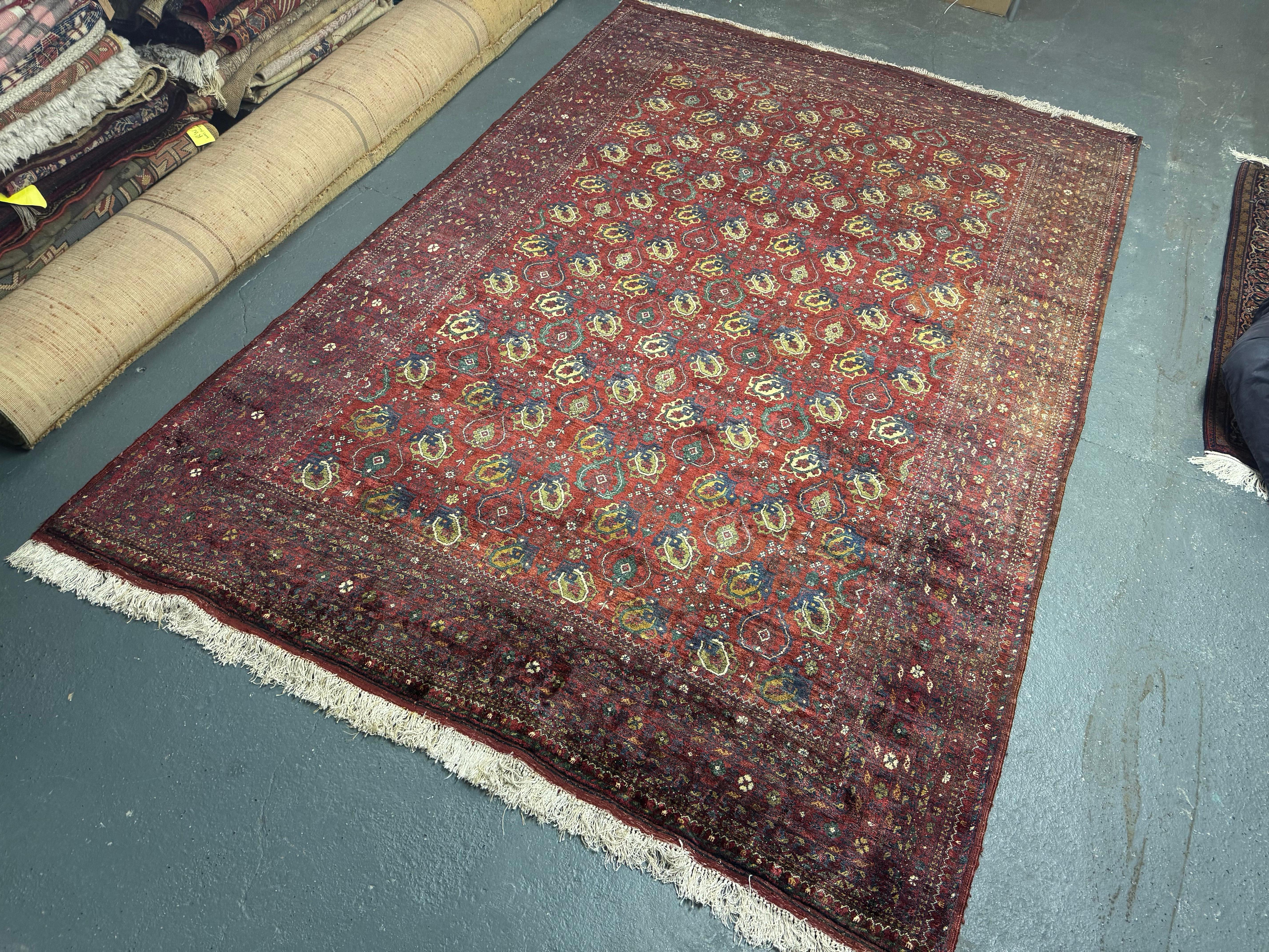 This grand hand-woven wool Afghan rug was woven in Iran in the 1960s. Woven with a beautiful colour palette including rust, blue, gold, brown and black accents that make up an elegant repeat design. Framed by a bold repeating pattern border. Vintage