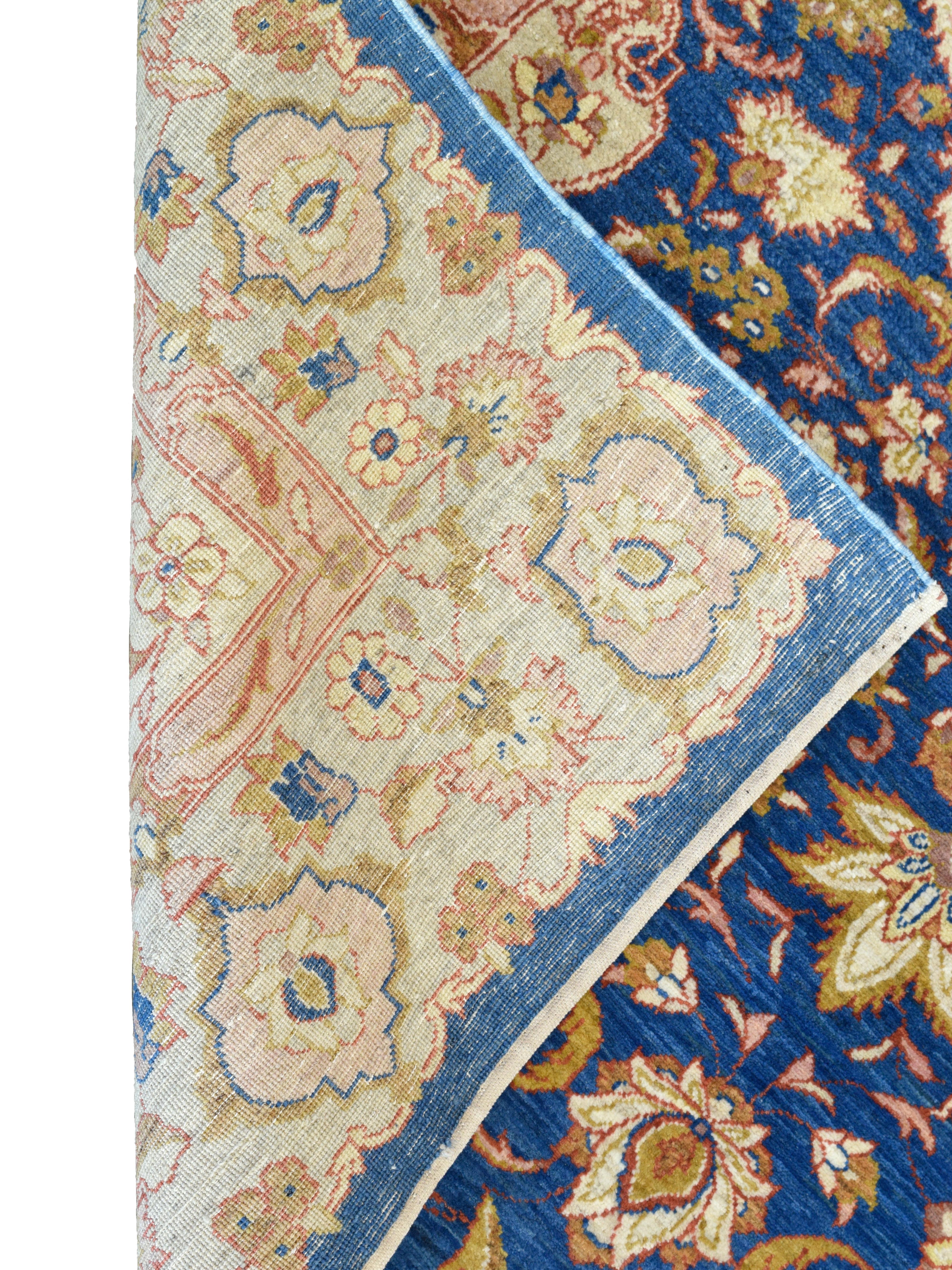 Questo tappeto persiano annodato a mano di 4' x 6' mette in mostra la raffinata eleganza associata al classico design Farahan, celebrato per la sua composizione equilibrata, la tavolozza luminosa e il disegno meticoloso. Il ricco campo blu cobalto