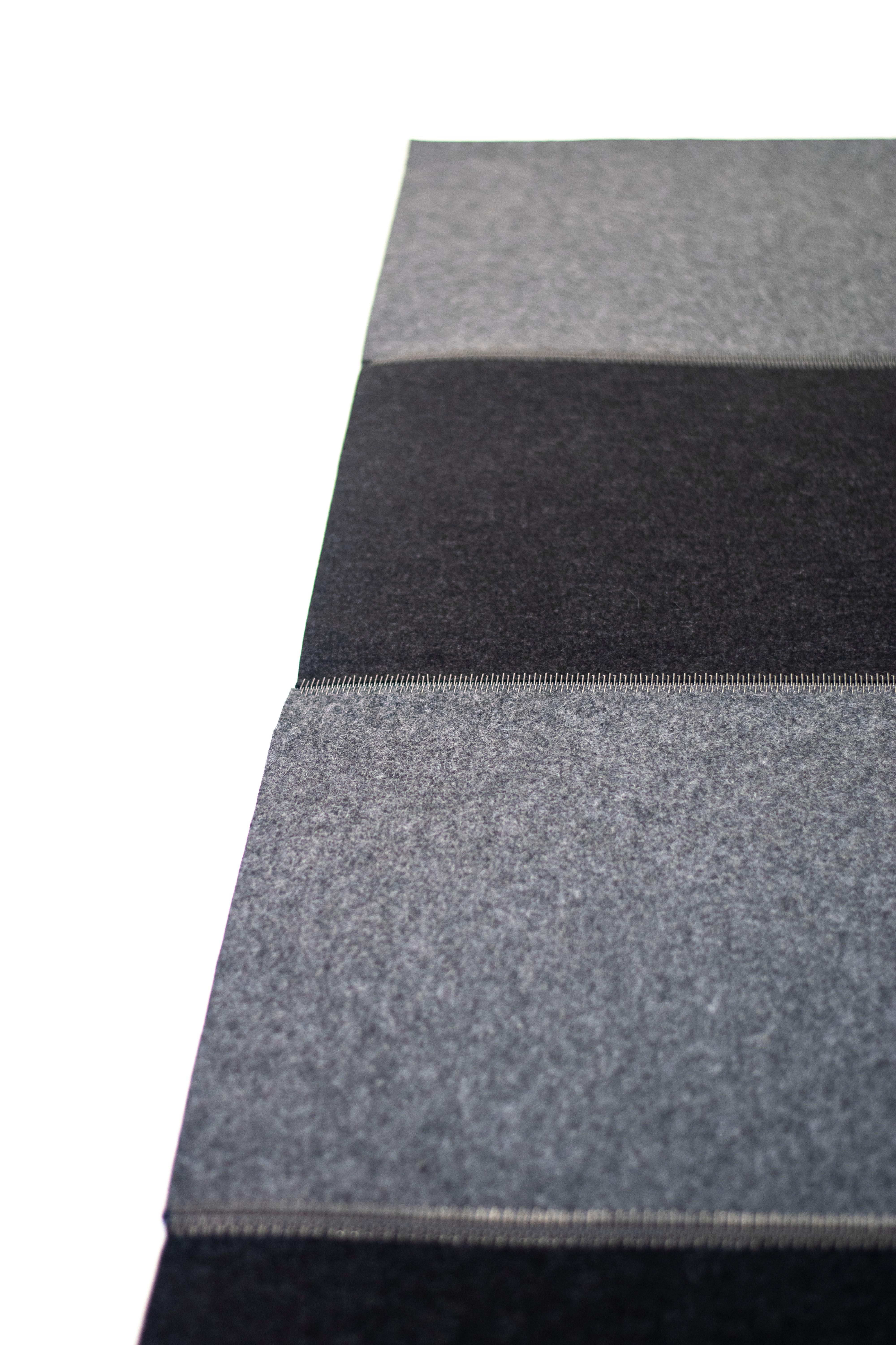 Industrial zip-hinge steel lacing connects 100% wool felt flooring. Colors used are medium graphite grey and dark anthrazit grey, alternating.