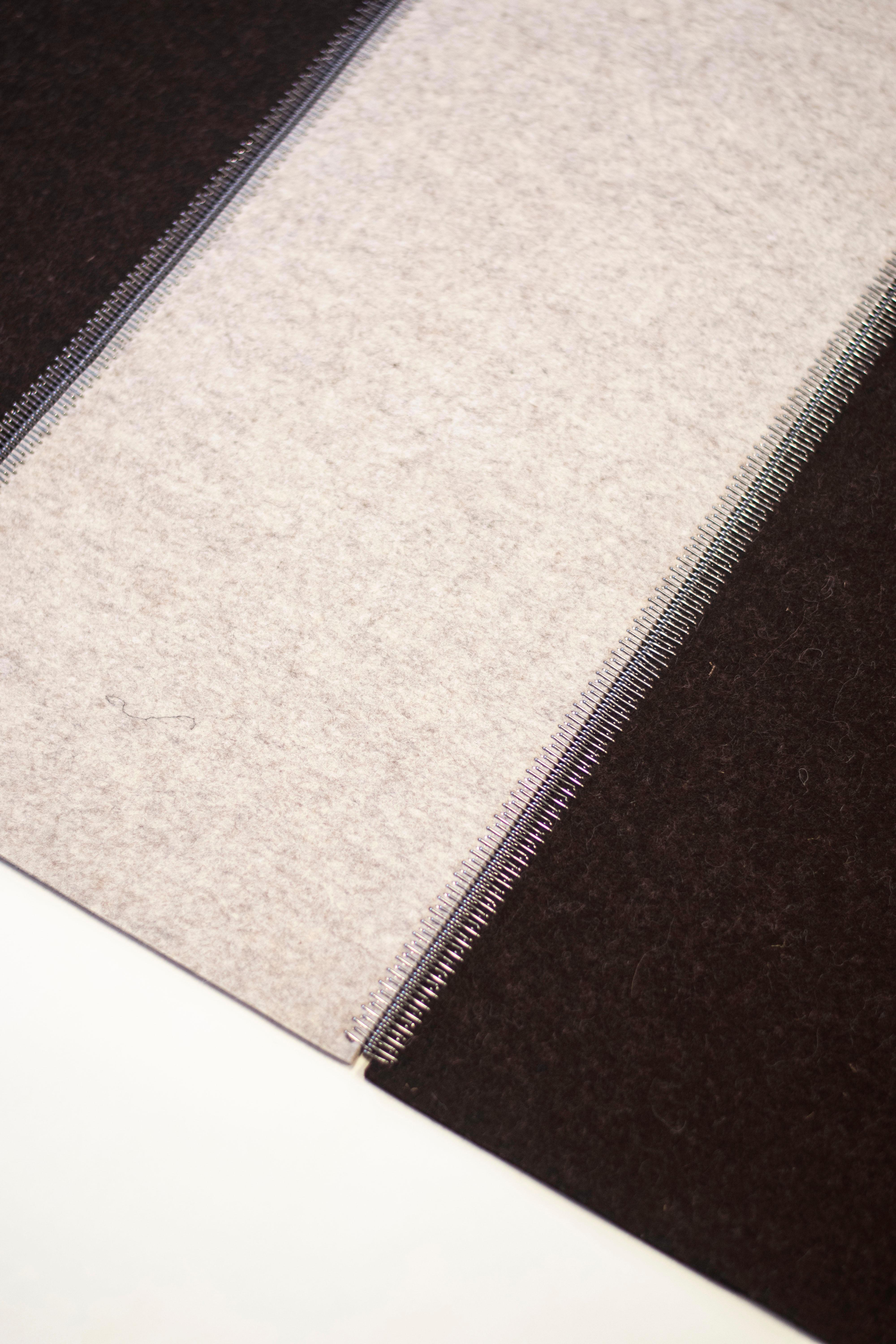 Industrial zip-hinge steel lacing connects 100% wool felt flooring. Colors used are Truffle Braun dark brown with beige sandwiched in between.