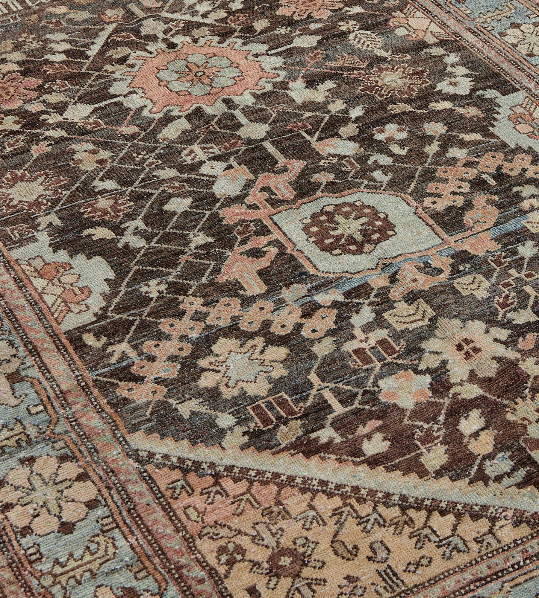 This antique Bakhtiari runner has a charcoal-brown field with central column of light blue and terracotta-red palmettes linked by a dense profusion of angular palmette and floral vine, part similar palmettes at each side, soft terracotta-pink