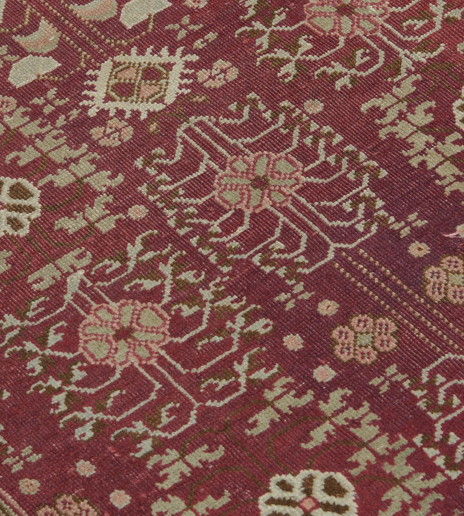 This antique, circa 1900, Agra runner has a shaded blackcurrant-red field with an overall design of vertical rows of ivory and buff-brown floral sprays enclosing a single rosette alternating with a similar central rosette issuing angular flowerhead