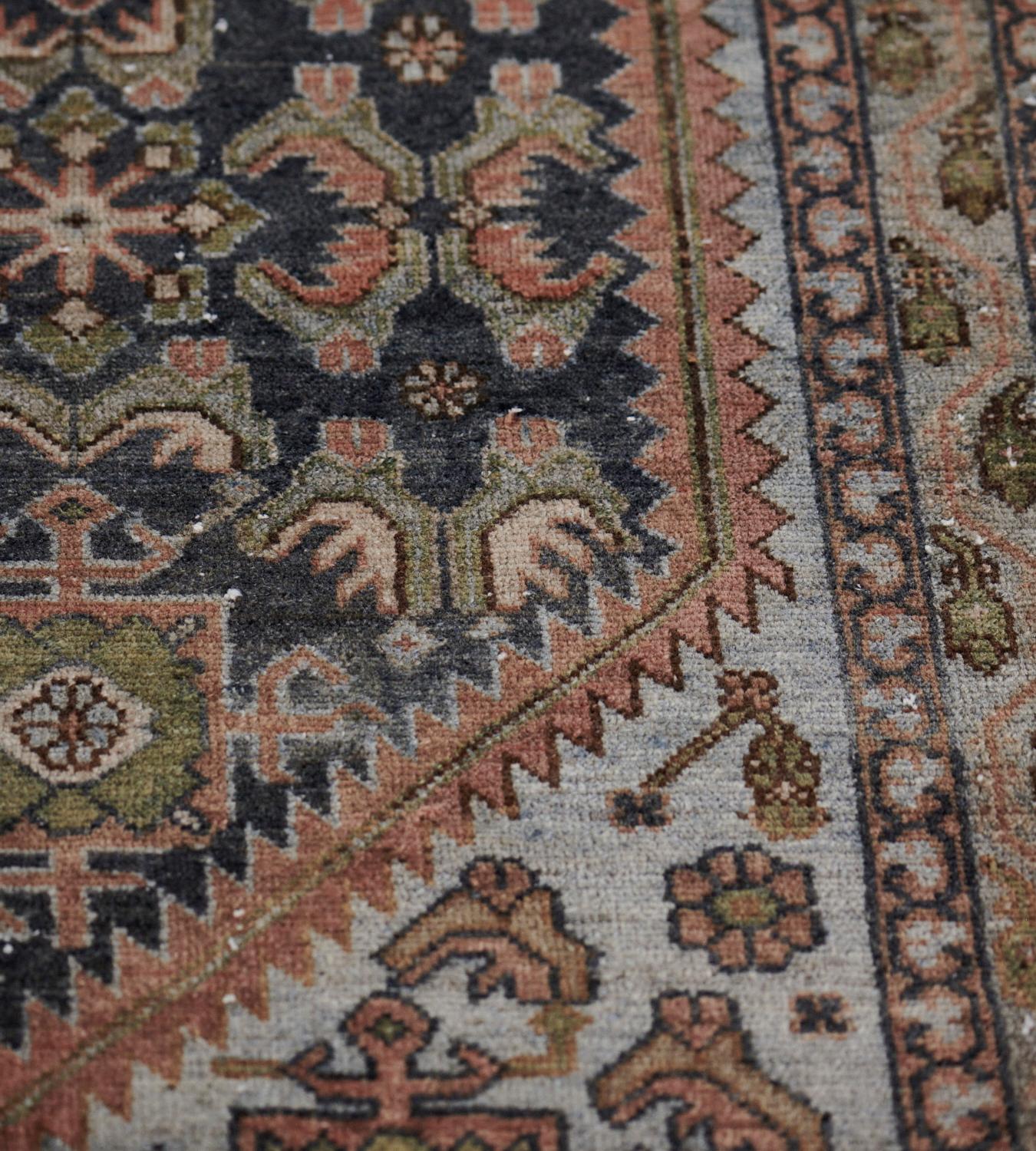 This antique Malayer rug has a shaded deep blue field with a dense angular palmette and serrated leaf vine around horizontal rows of brick-red square panels each containing a moss-green palmette, the light blue linked spandrels similar, in a shaded