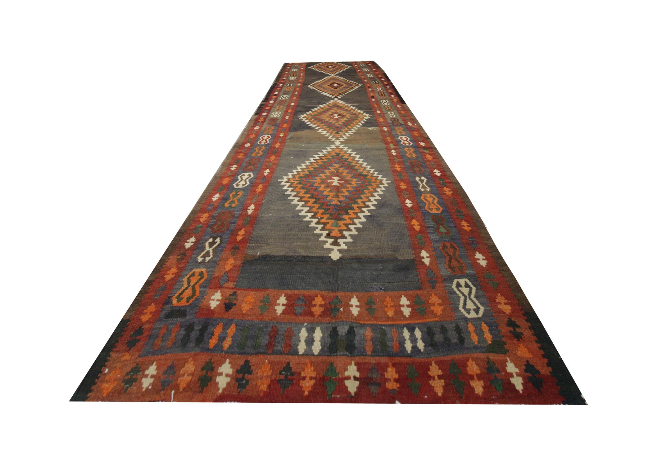 The subtle tones in this tribal Kilim rug are sure to complement your home's interior. Featuring a bold central design with four diamond motifs woven in orange, beige and cream on a grey-brown background. Framed with a repeating pattern tribal motif