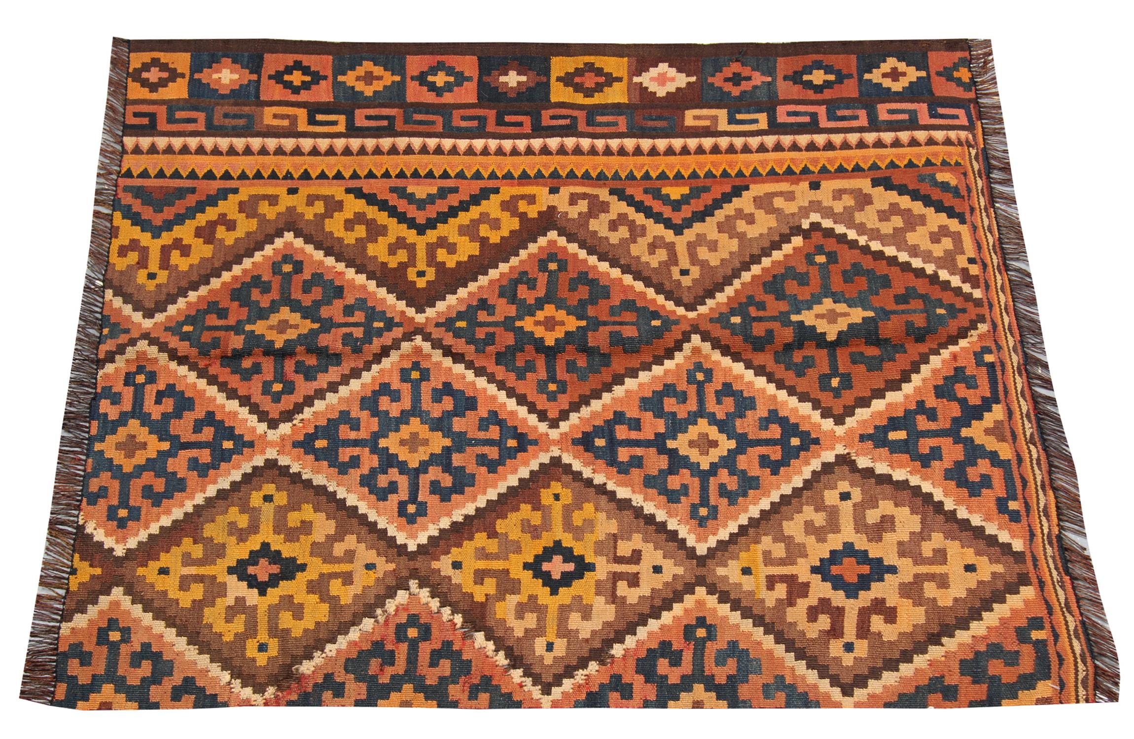 Orange, deep blue and brown are the main colours in this fine wool rug. Featuring a repeating pattern hook motif design that covers the bottom half of this piece with a one-sided border with zig-zag and tribal motifs in a repeating pattern. This