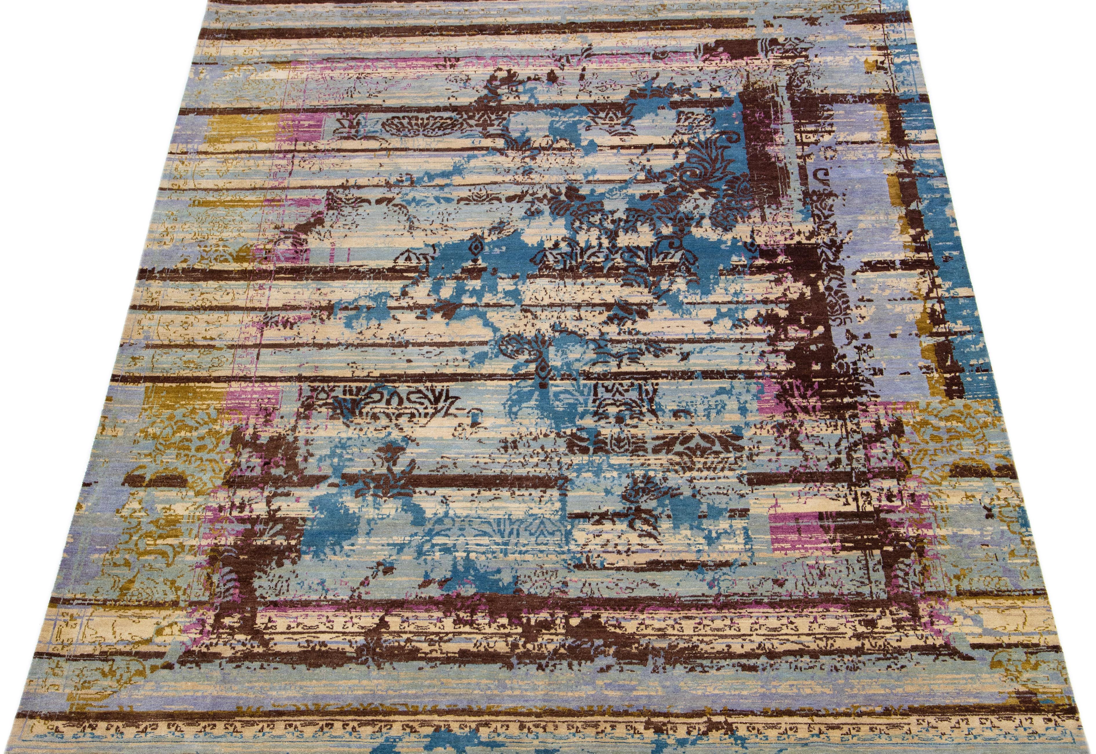 Questo tappeto tibeto-indiano in misto lana e seta presenta un campo grigio chiaro e beige con un motivo astratto dai colori blu, marrone e rosa. I materiali di cui è composto garantiscono robustezza e longevità, mentre il suo design ornamentale