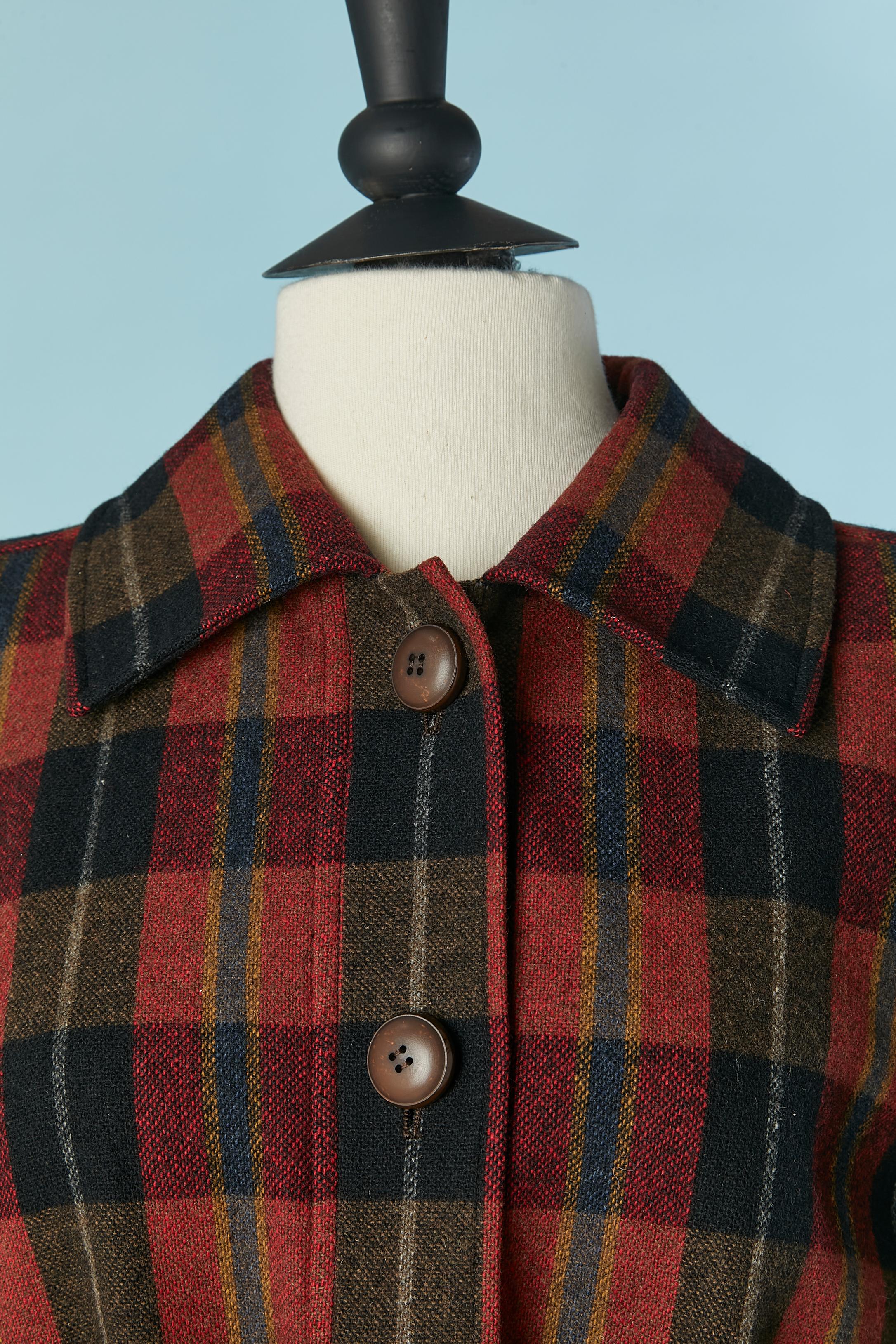Cappotto monopetto in lana con motivo Tartan. Spallaccio. Non c'è l'etichetta della composizione del tessuto, ma la fodera è probabilmente in rayon o acetato. 
Chiusura con bottoni e asole sulla parte centrale del davanti + sul retro sulla cintura.