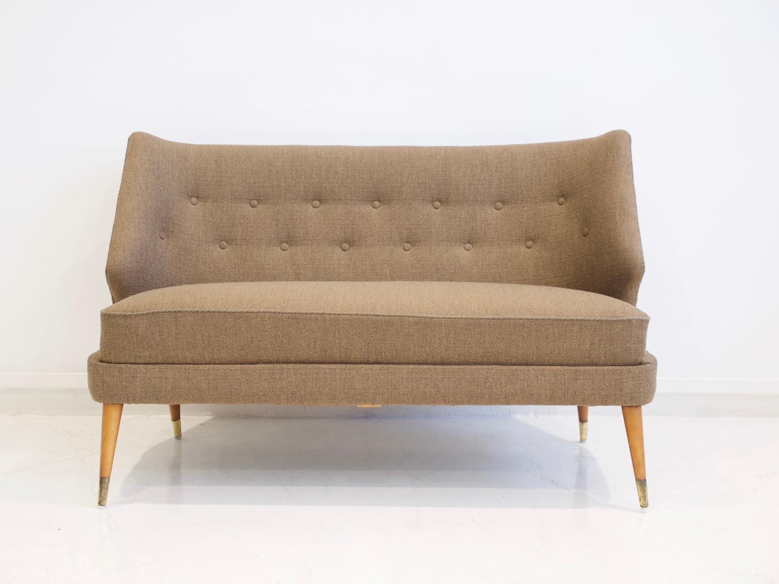 Mid-20th century sofa with beautifully curved button tufted back. Upholstered in light brown wool, stained beech legs with brass finish. Designed by Arne Wahl Iversen.