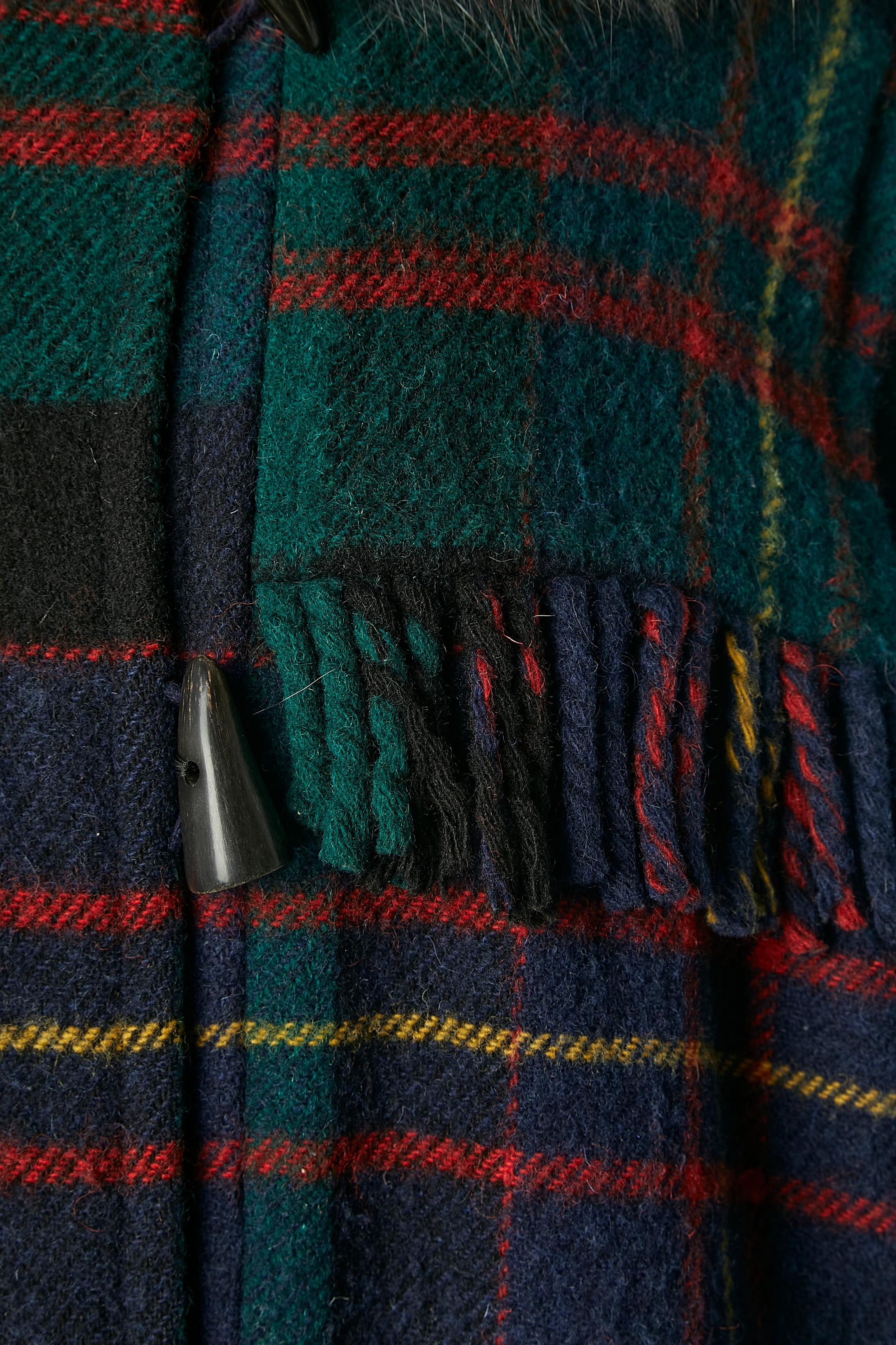 Schottenkaro gesteppter Dufflecoat aus Wolle mit mehrfarbigem Pelzkragen (in den gleichen Farben wie der Mantel). Hornknopf in der vorderen Mitte und Knopfloch. Hornknöpfe auch an den Manschetten (kein Knopfloch) 
Tasche auf beiden Seiten. Fransen