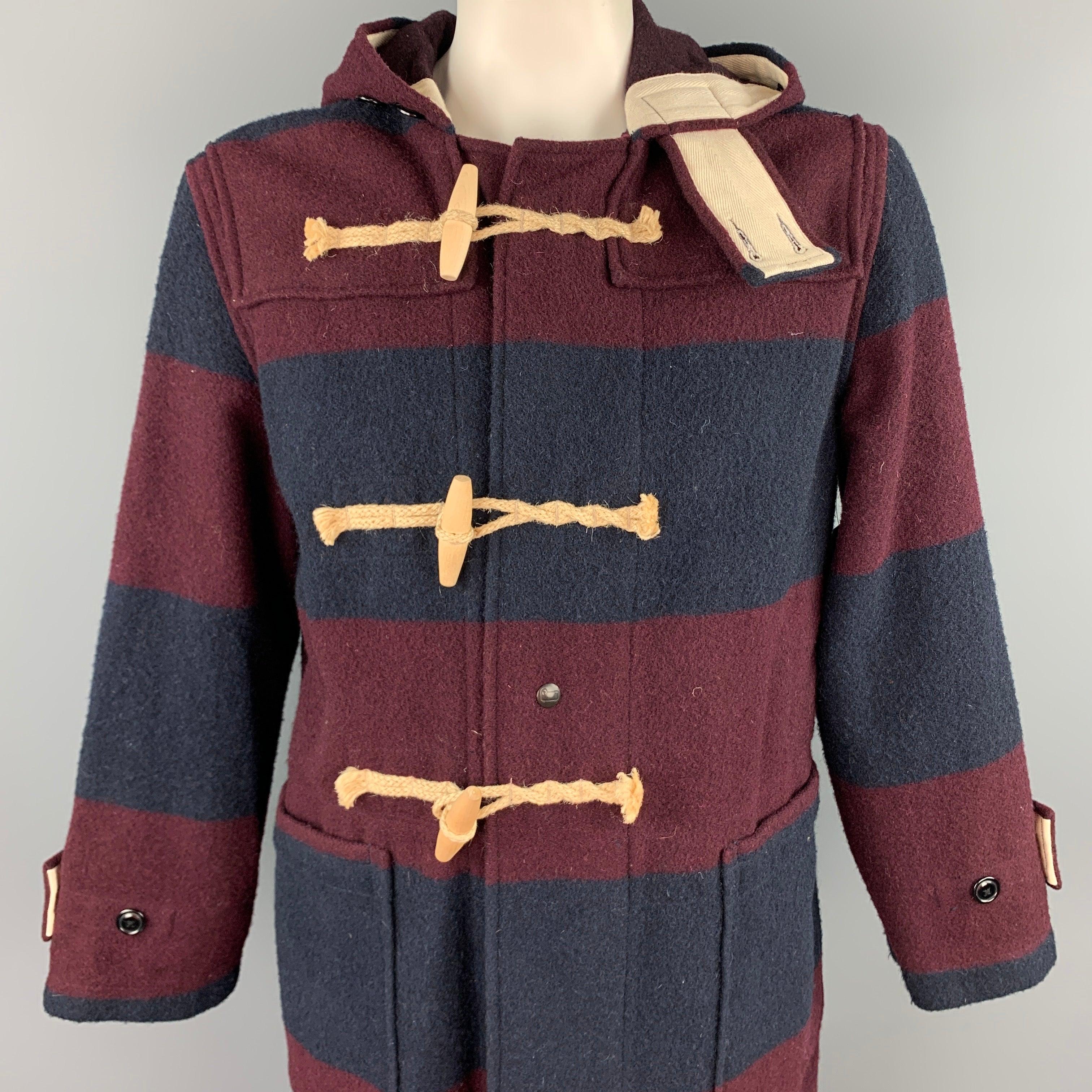 WOOLRICH coat comes i a burgundy & navy stripe wool / nylon featuring a hooded style, patch pockets, buttoned details, and a toggle closure. Made in USA.
Good
Pre-Owned Condition. 

Marked:  M 

Measurements: 
 
Shoulder: 20 inches Chest: 46 inches