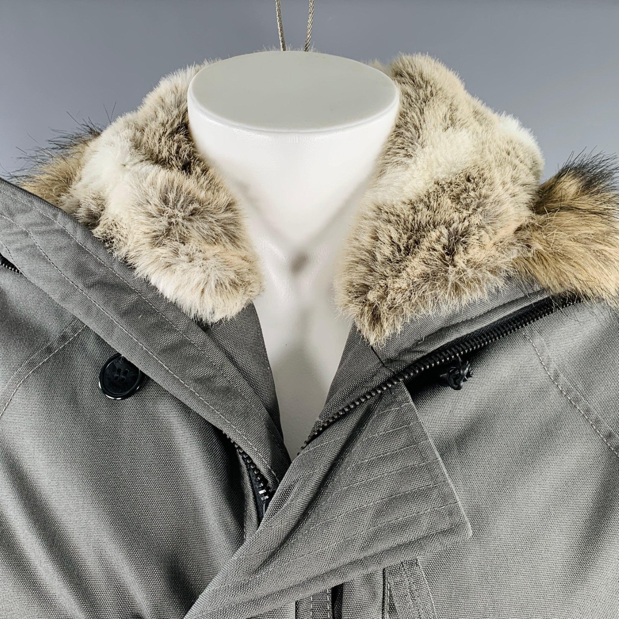 WOOLRICH jacket
in a grey nylon featuring a hooded style with faux fur trim, snap pockets, and zip & buttons closure. Excellent Pre-Owned Condition. 

Marked:   M 

Measurements: 
 
Shoulder: 17 inches Chest: 41 inches Sleeve: 27 inches Length: 28