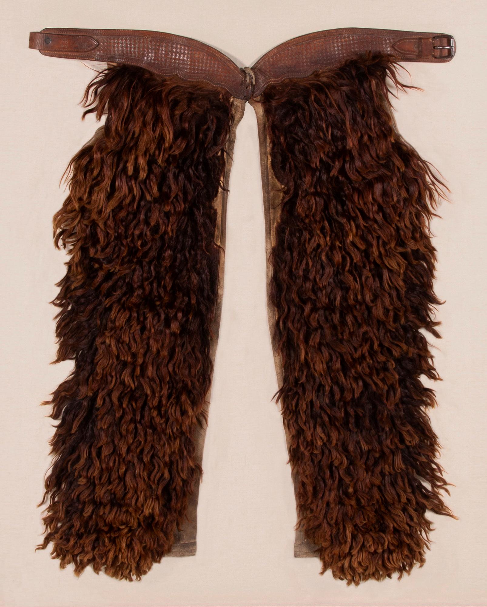 WOOLY, Angora chaps with beautifully tooled leather, made by the JOHN CLARK SADDLERY COMPANY OF PORTLAND, OREGON, SIGNED, CIRCA 1873-1929

Wooly chaps made of leather and canvas, faced with dyed Angora, made by the John F. Clark Saddlery Company
