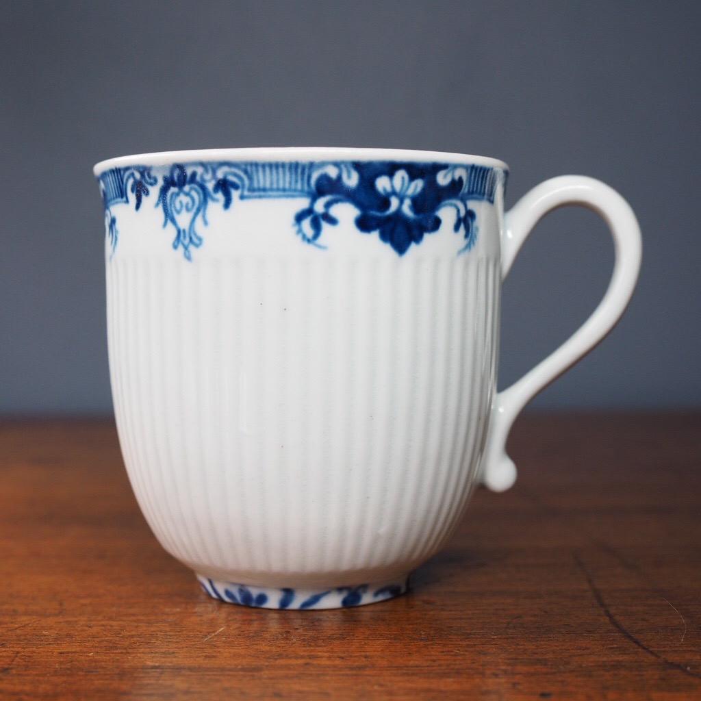 A fine Worcester cup & saucer, after a French design with ribbed moulding, the saucer with a raised 'trembleuse' ring, the rims painted in underglaze blue with a lambrequin border.

Crescent mark, circa 1756.
 