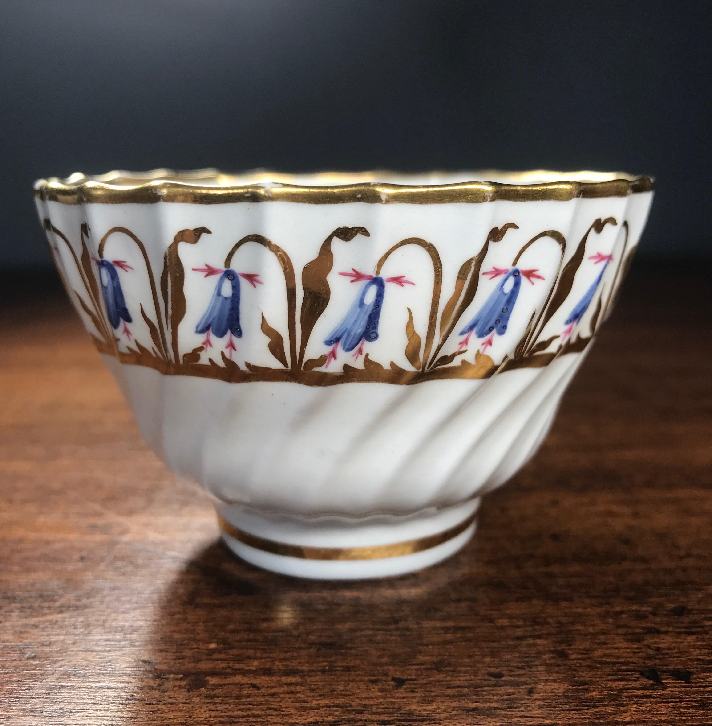 Flight & Barr Worcester teabowl & saucer, the spiral fluted forms painted with a blue bellflower border, set in a wide gilt border, the cup with a fine gilt foliate band within, a large flower sprig to the base of each.
Unmarked, c. 1795

The