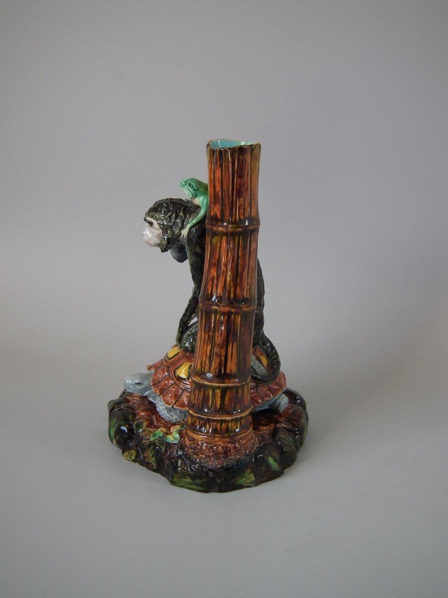 Vase en majolique de Royal Worcester représentant une grenouille sur le dos d'un singe, lui-même assis sur le dos d'une tortue. Un vase en bambou derrière. Coloration : les couleurs vertes, brunes et turquoises sont prédominantes. La pièce porte les